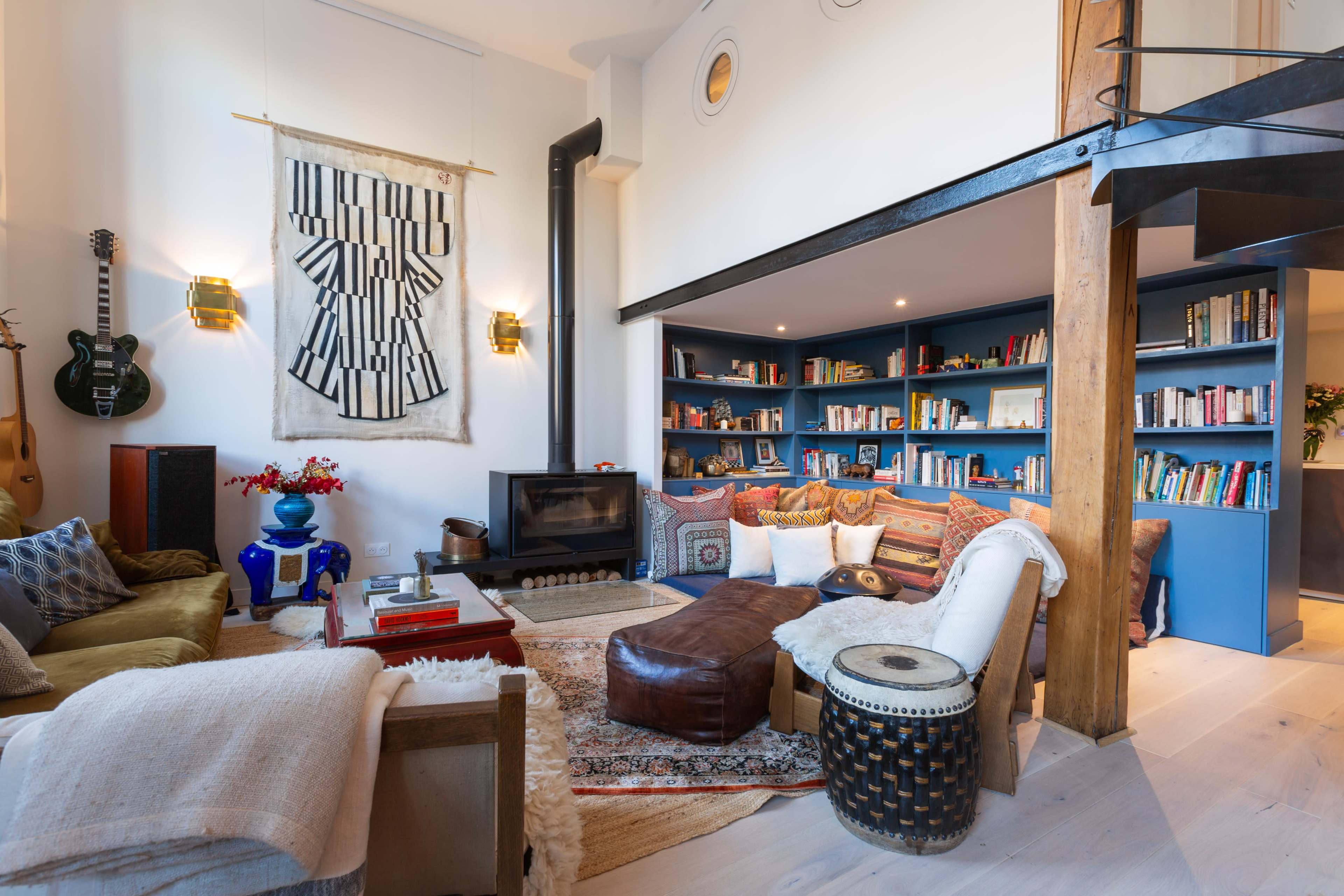 A cozy living room with a mix of seating, a fireplace, a large bookshelf filled with books, and decorative items on display.