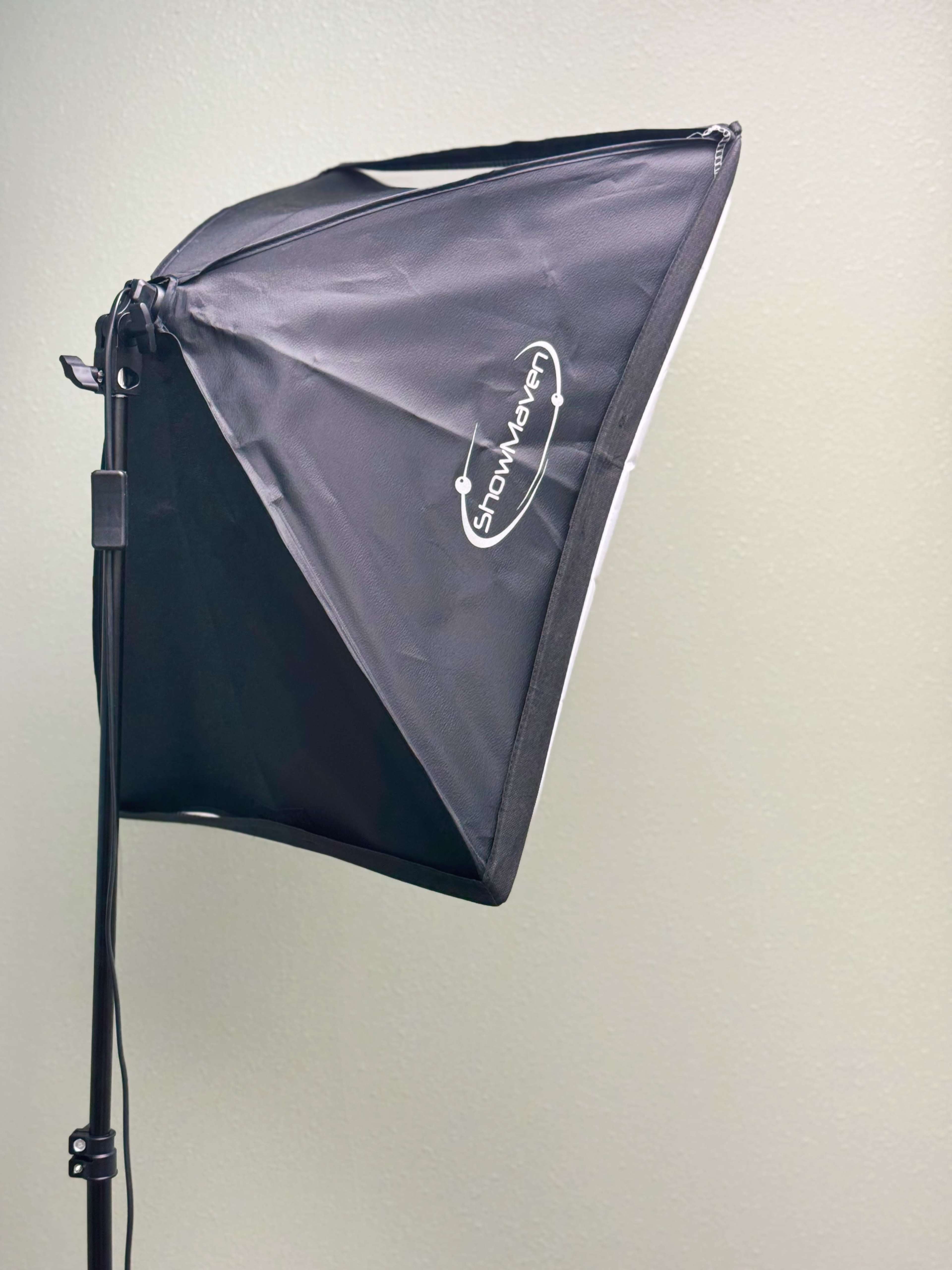 A softbox light is mounted on a stand against a plain wall.