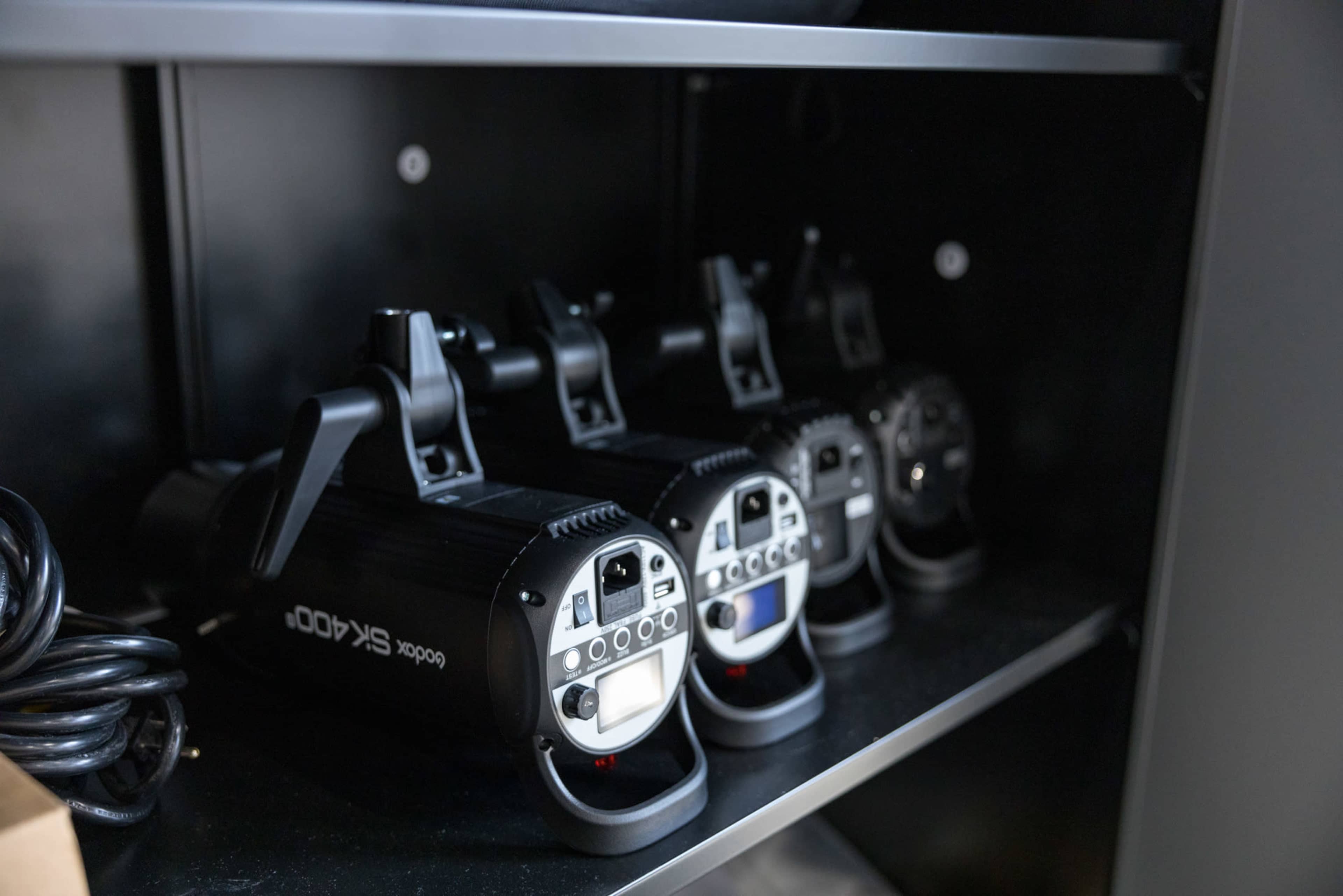 Three studio lights arranged on a shelf, each with control panels facing outward.