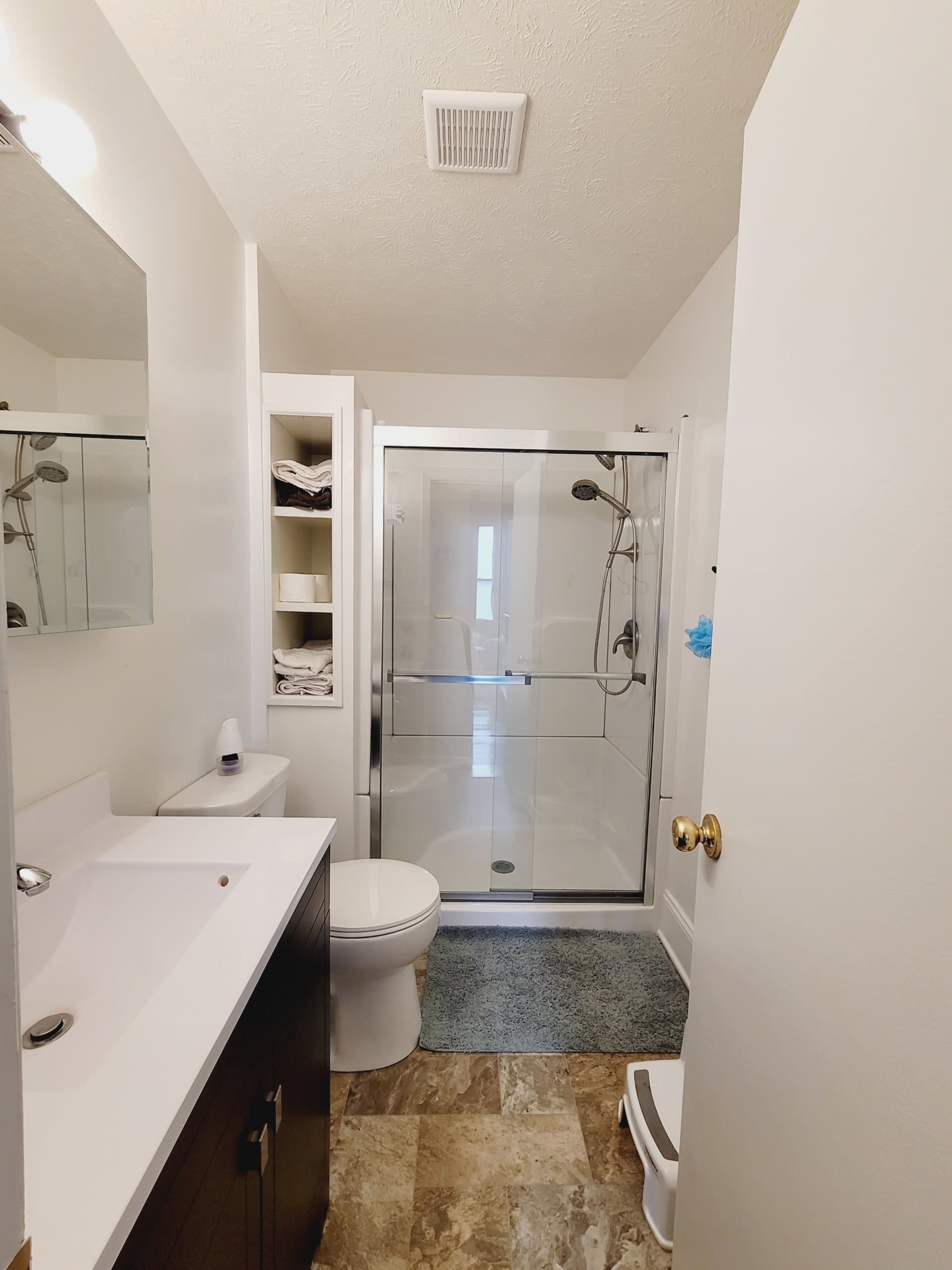 A clean bathroom with a glass shower enclosure, a toilet, and a vanity sink with a mirror above it.