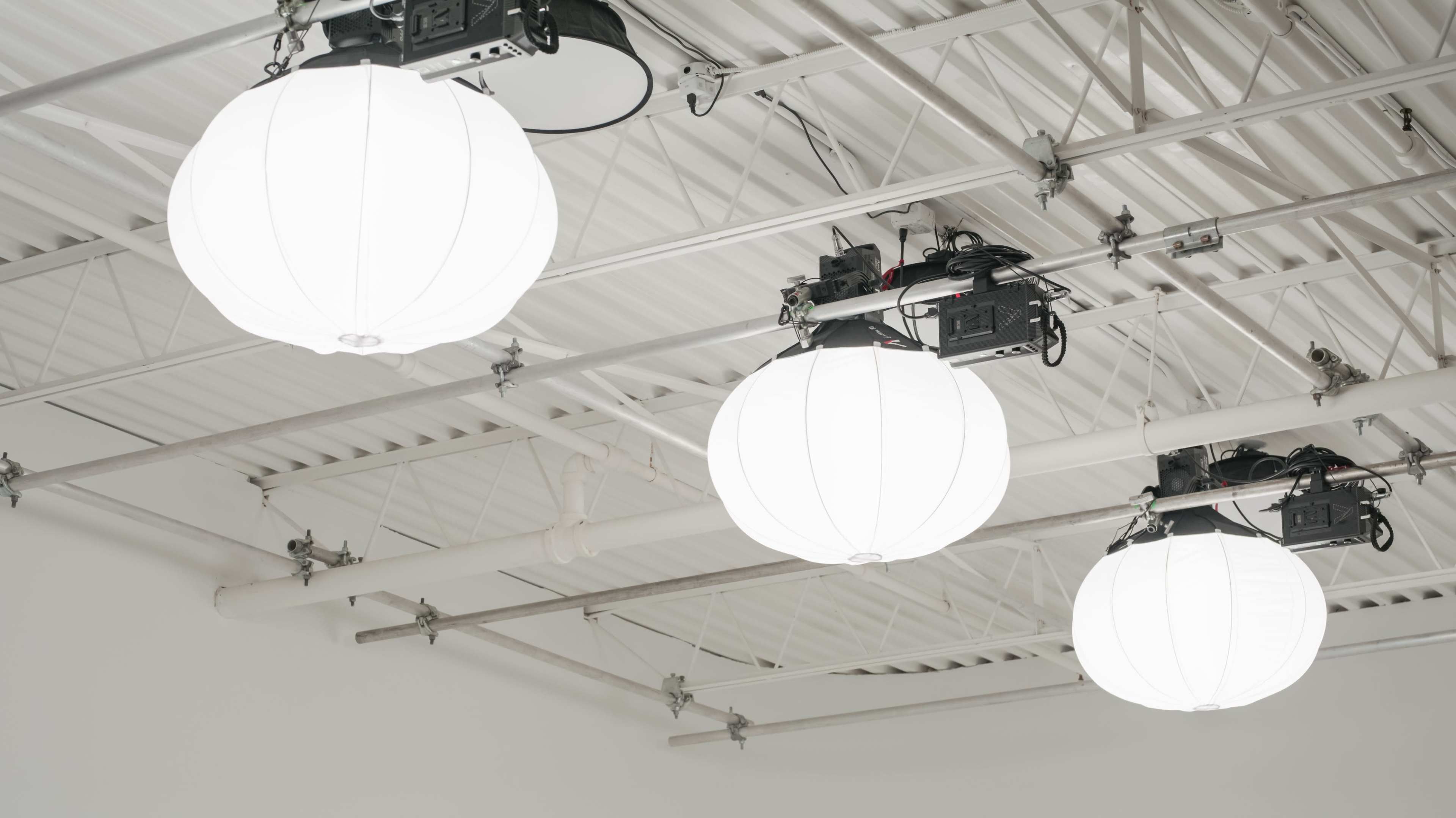 The image shows a ceiling with three large, spherical white light fixtures suspended from metal supports.