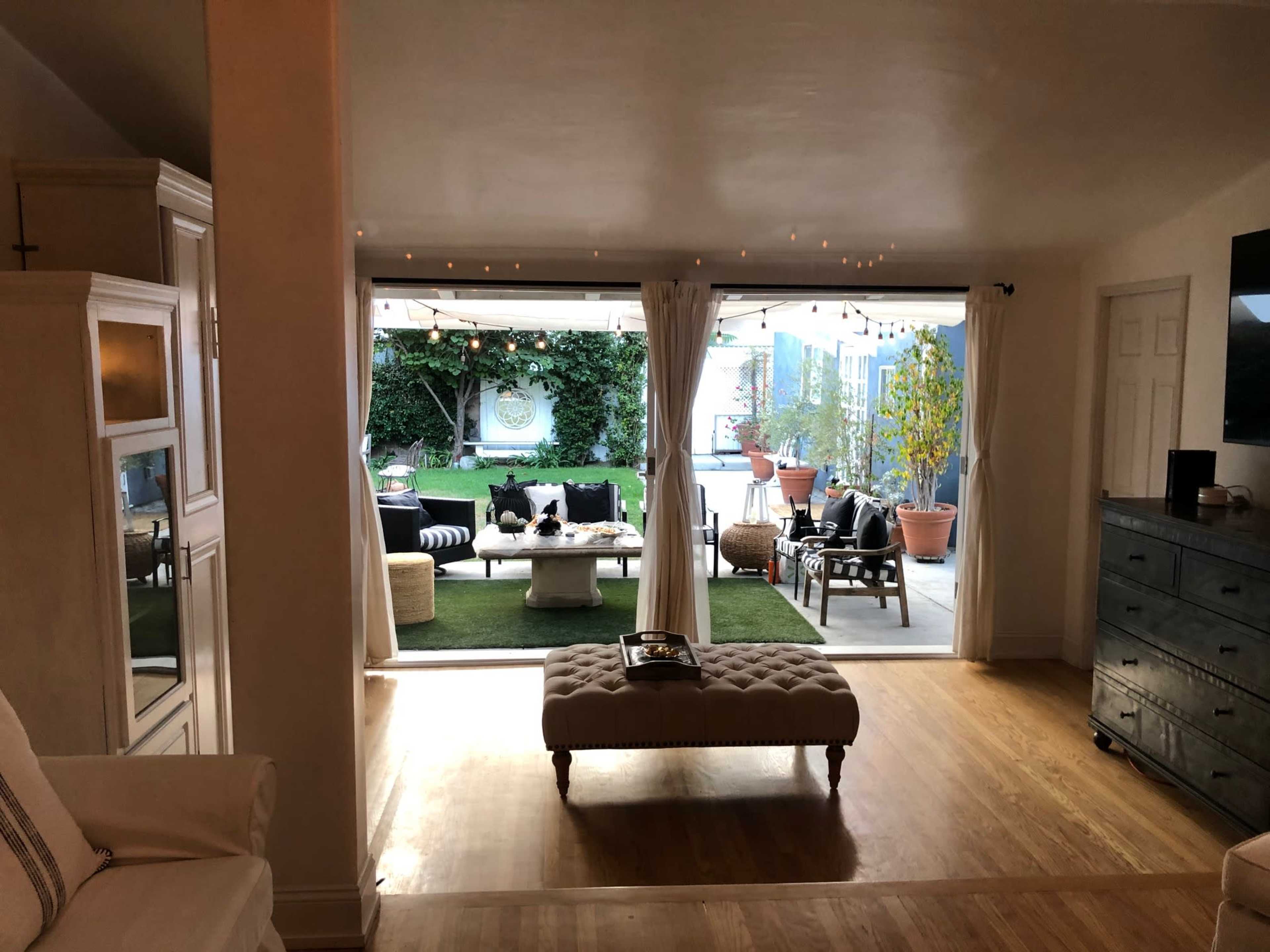 A spacious indoor living area opens up to a well-lit outdoor patio with seating and greenery.