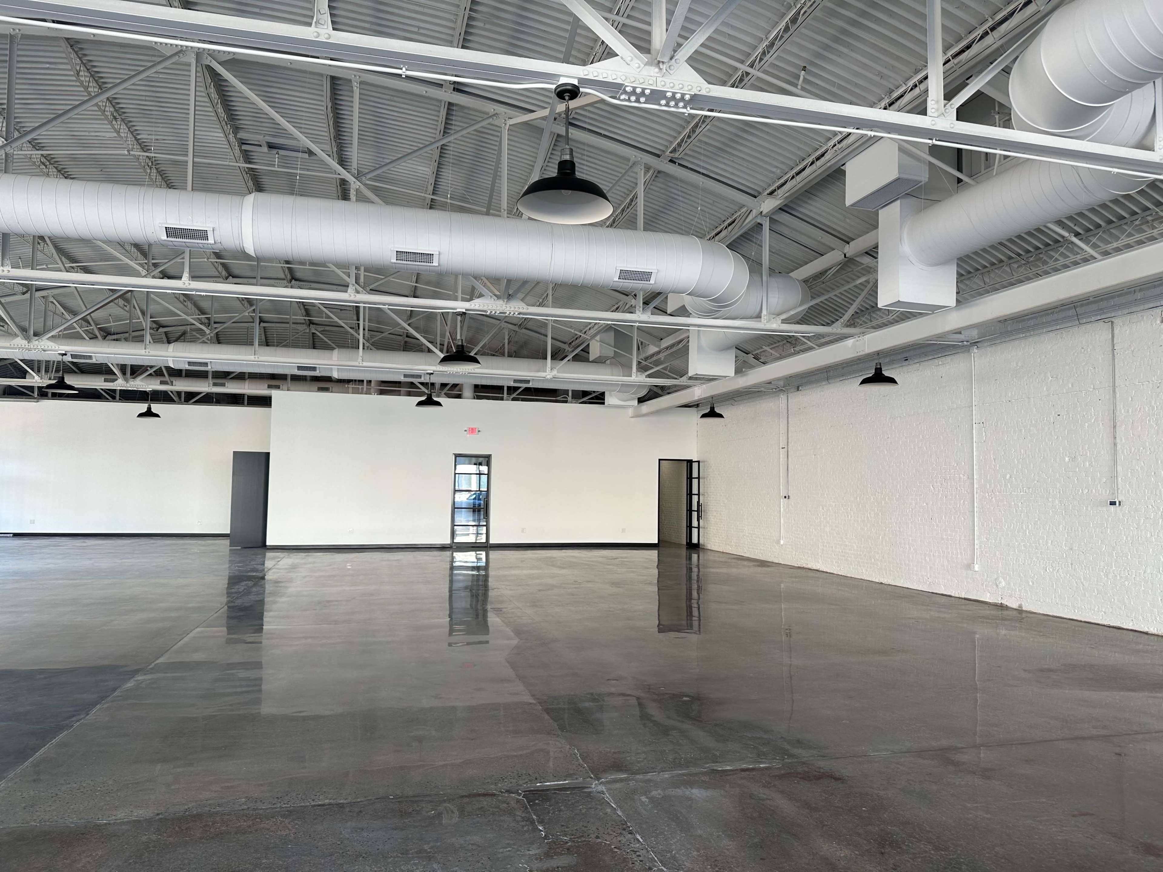 A large, empty commercial space with polished concrete floors and exposed ductwork on the ceiling.