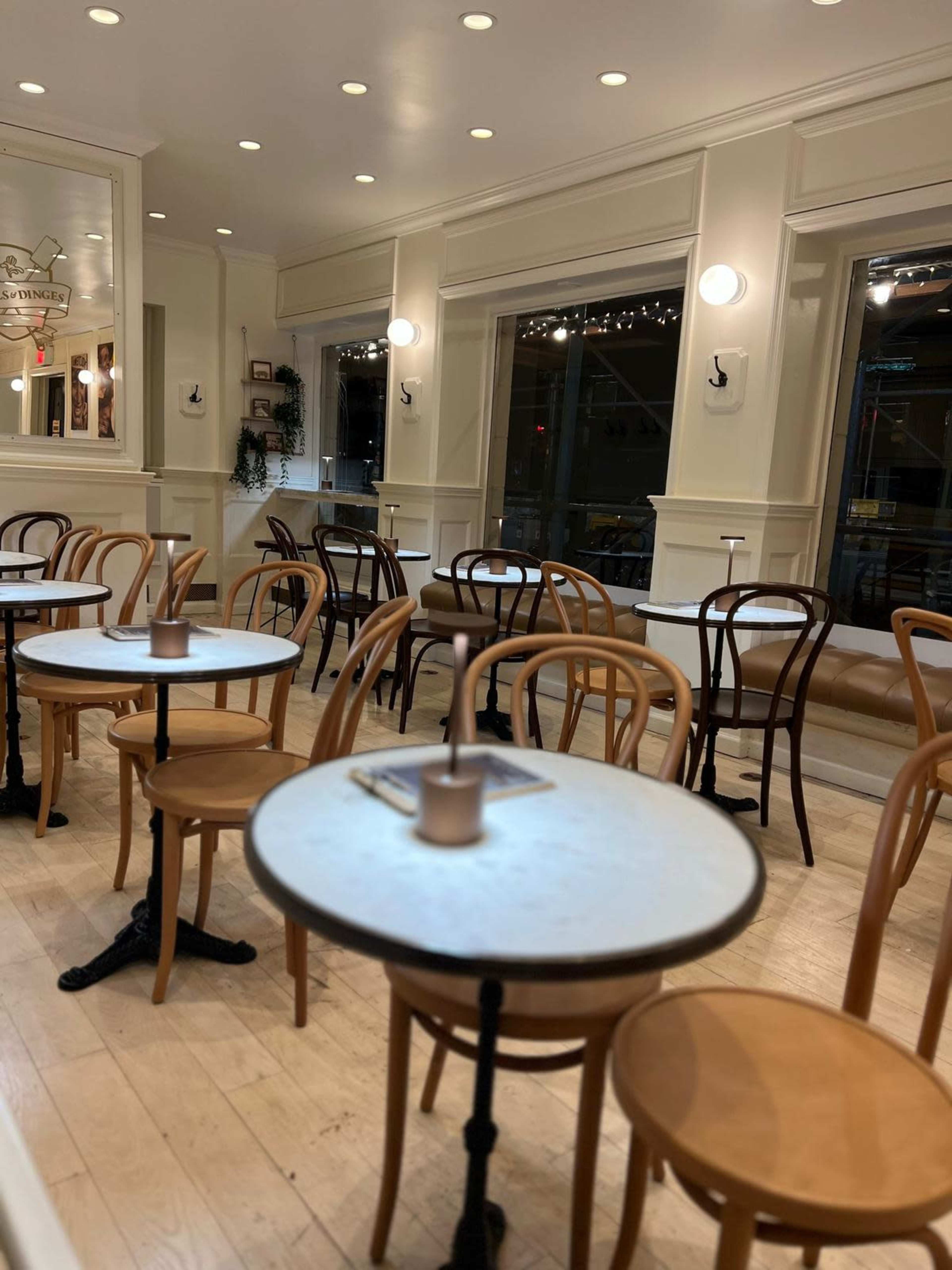 The café features several small round tables with wooden chairs arranged neatly around them.