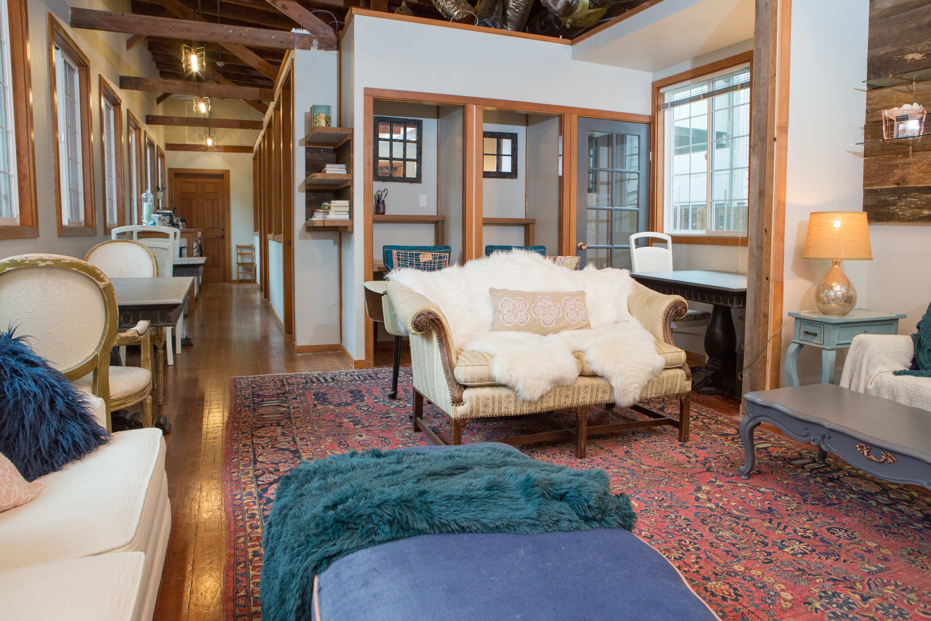 A cozy living space featuring a couch with a throw blanket, a coffee table, and a dining area in the background with wooden furniture and decorative elements.