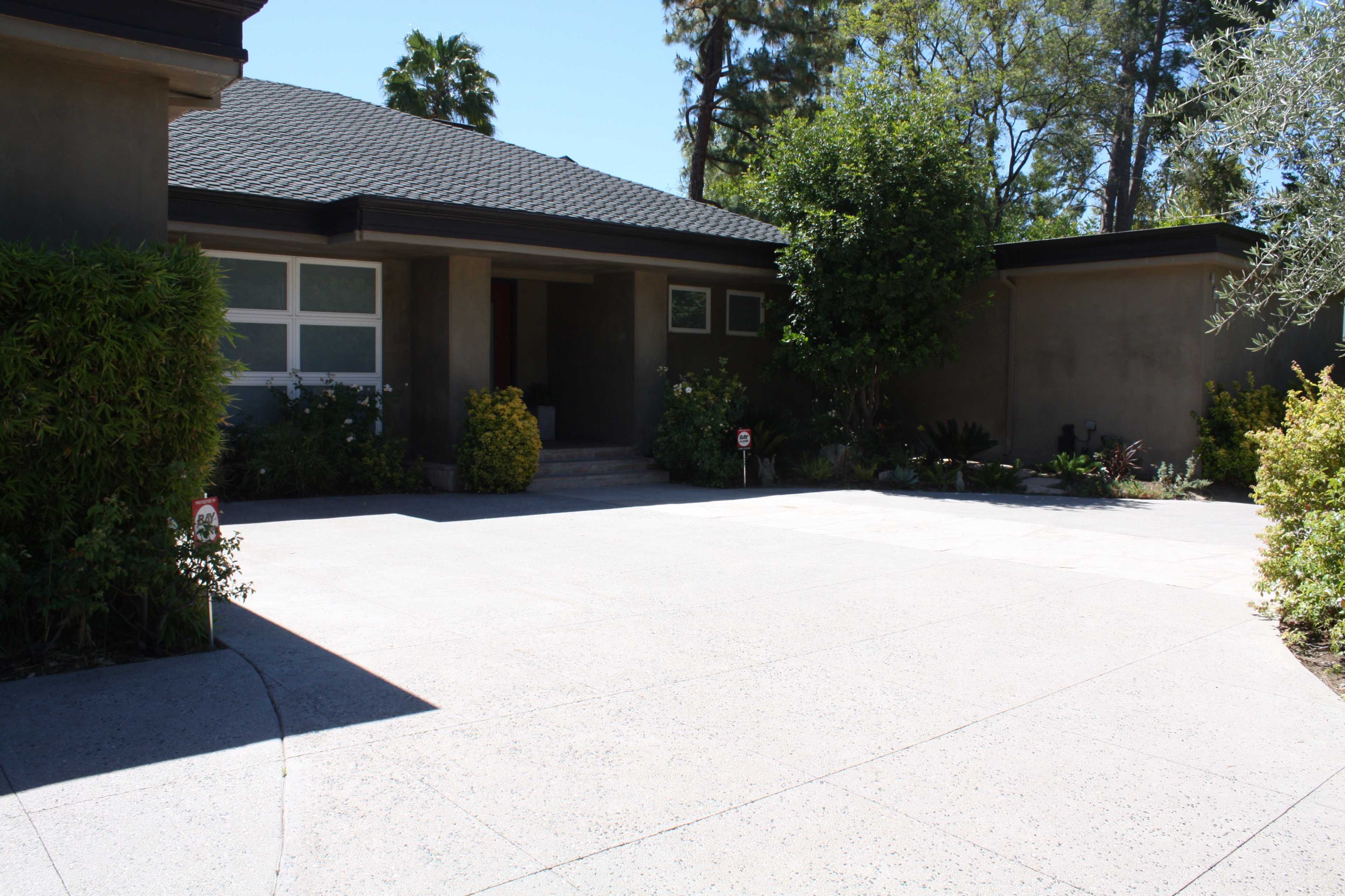 A modern house with a landscaped front yard and a spacious concrete driveway.