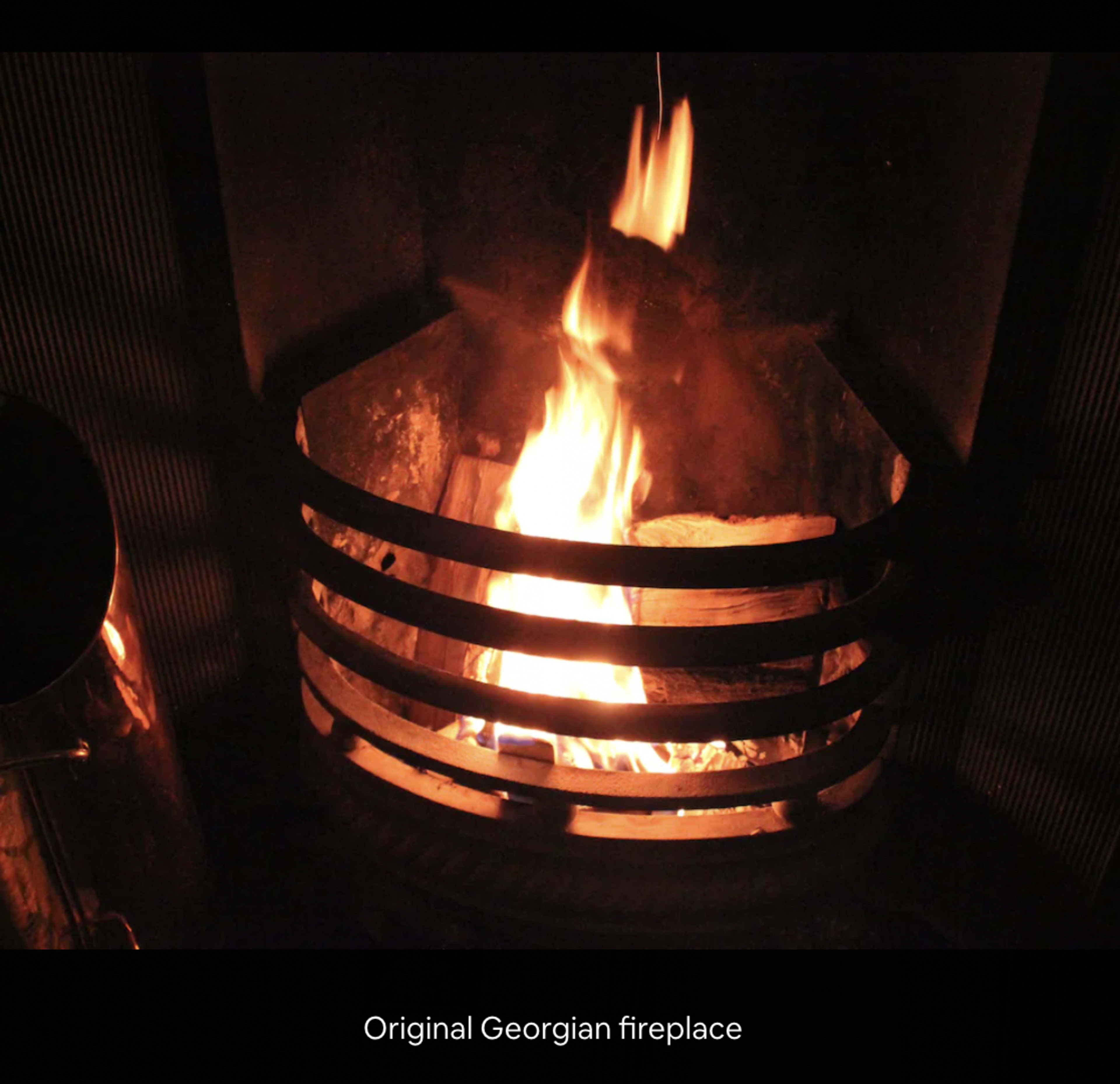 A fire burning in an original Georgian fireplace with a metal grate.