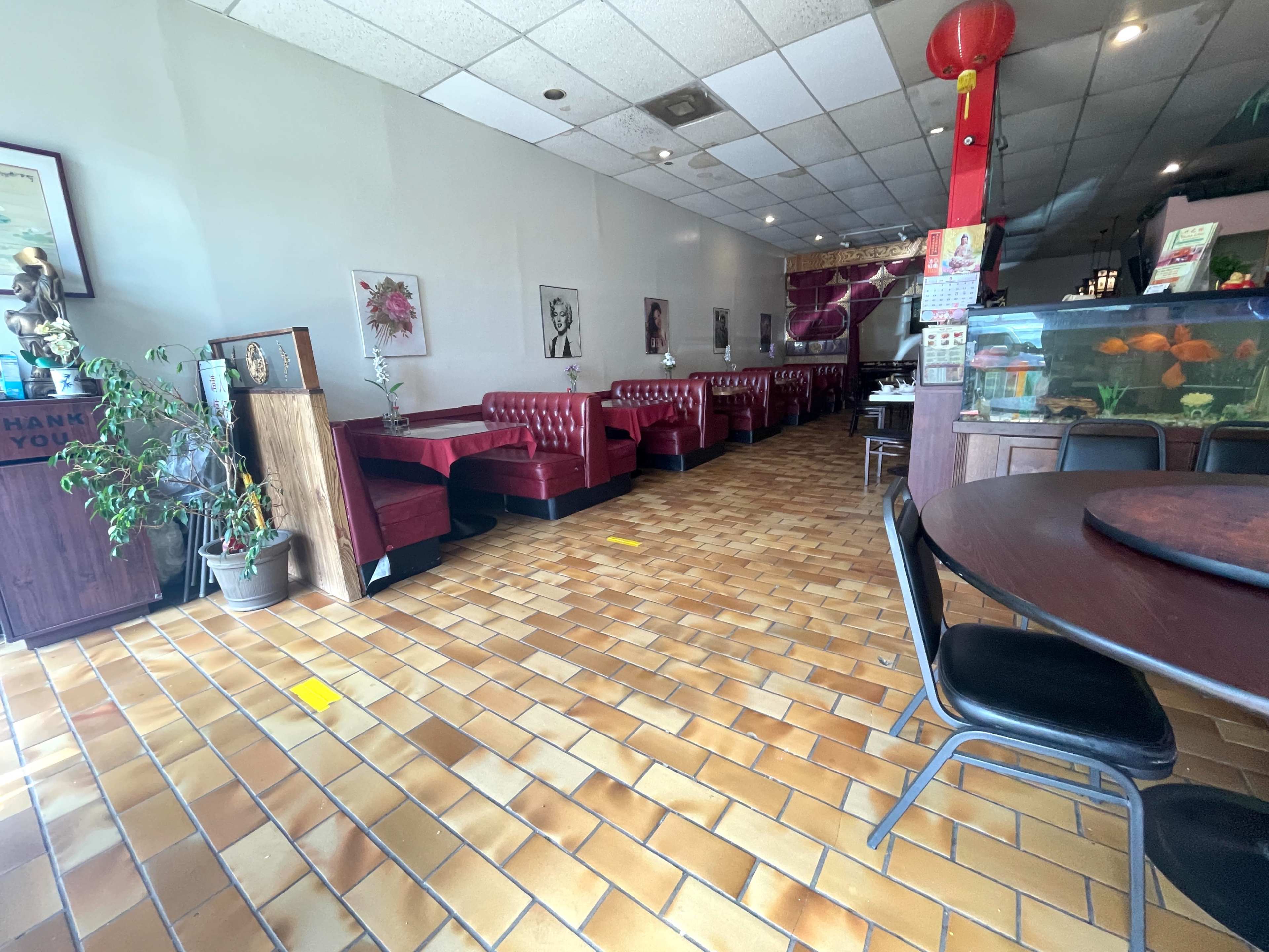 The image shows the interior of a restaurant featuring red booths, a tiled floor, and a fish tank in the background.