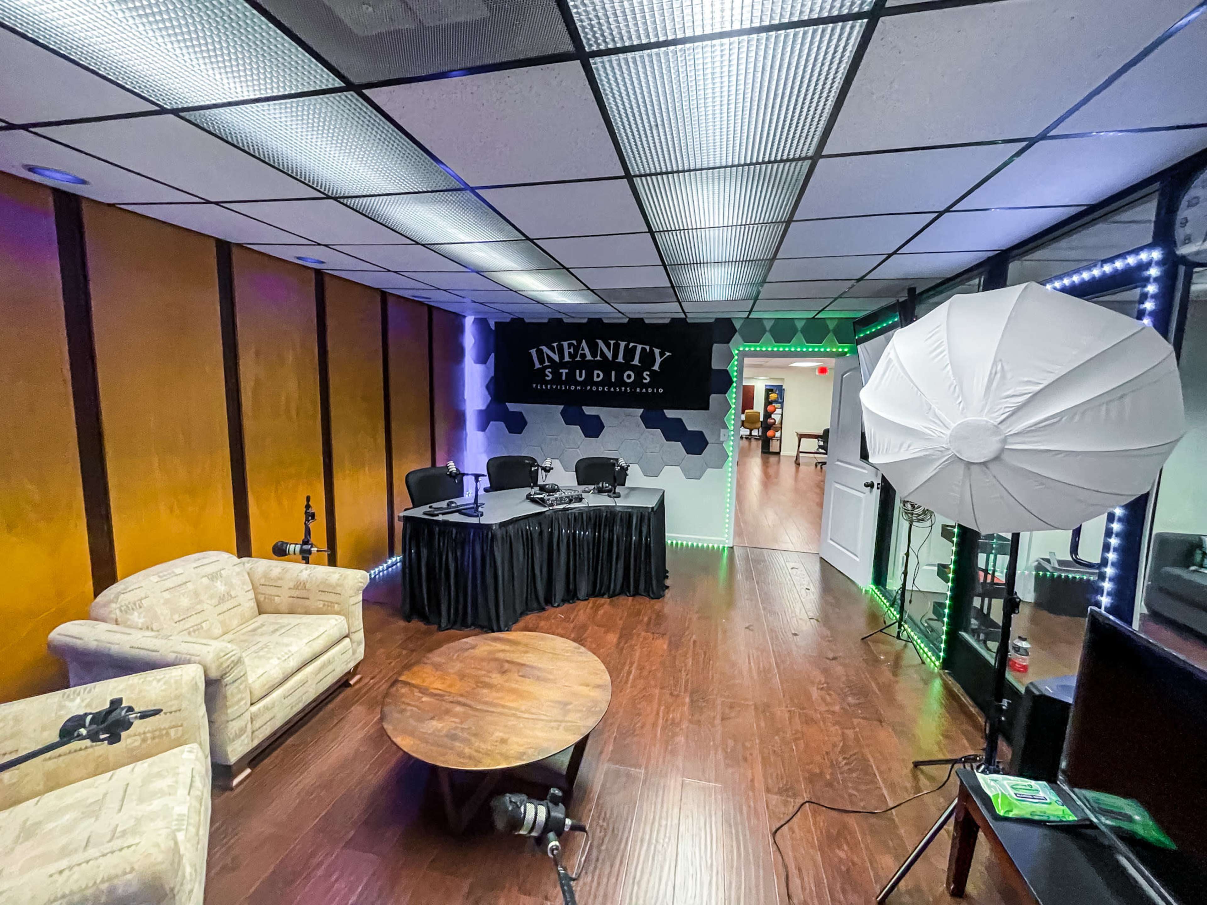 A studio room featuring a table with chairs, a circular table, and studio lighting equipment.