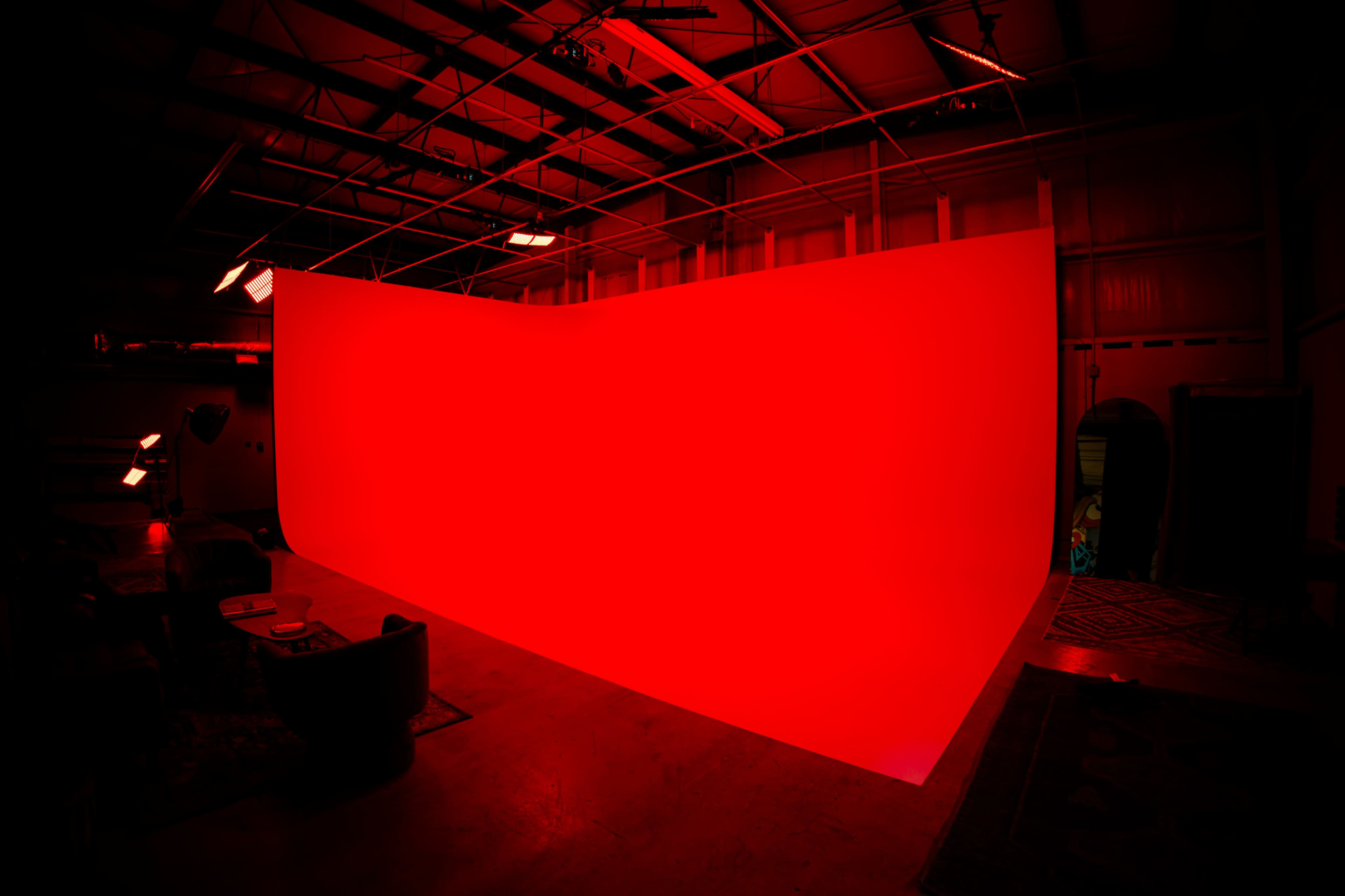 A large curved backdrop illuminated in red is positioned in an industrial space.