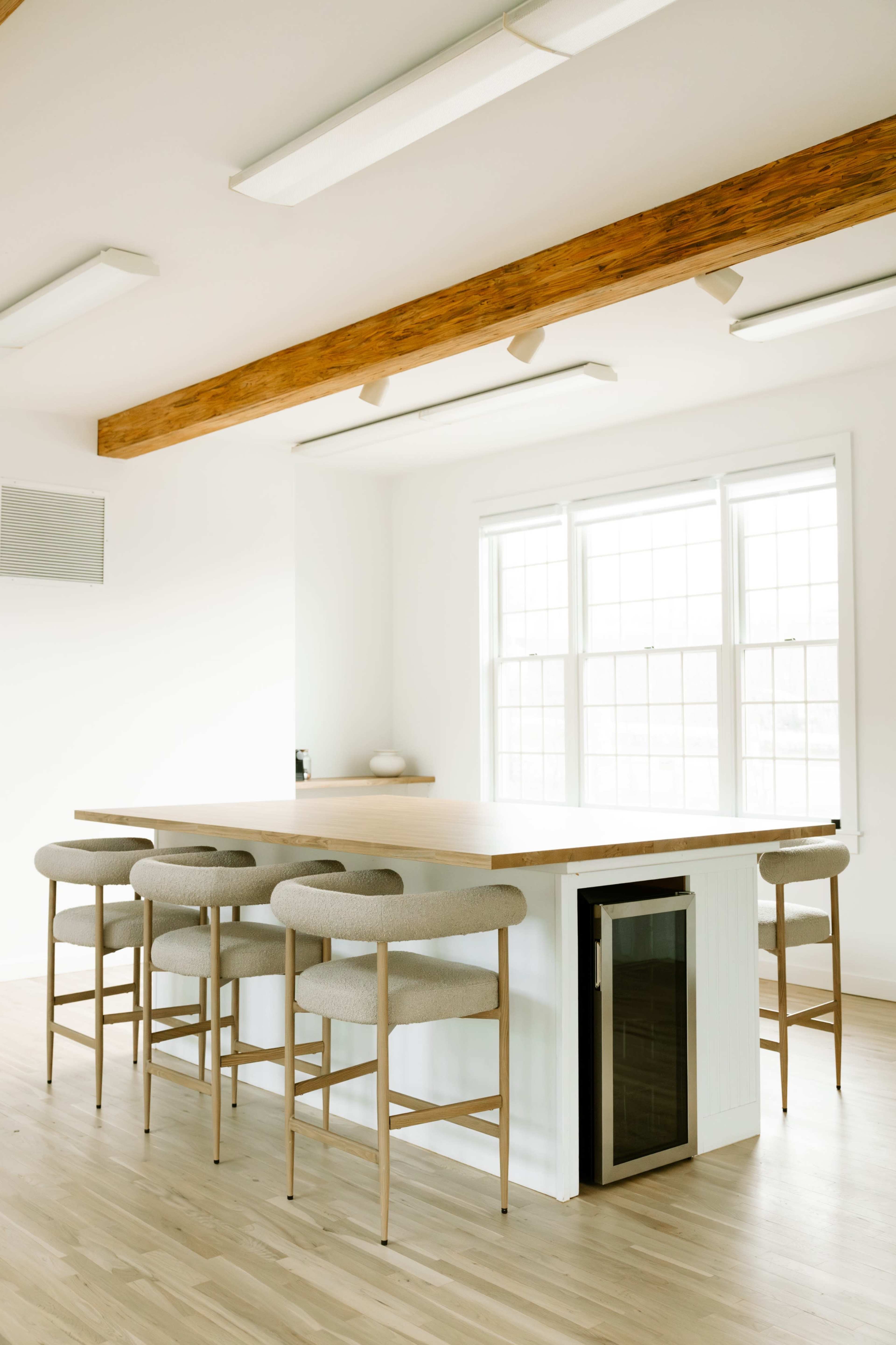 A modern kitchen area features a large island with bar stools and windows providing natural light.
