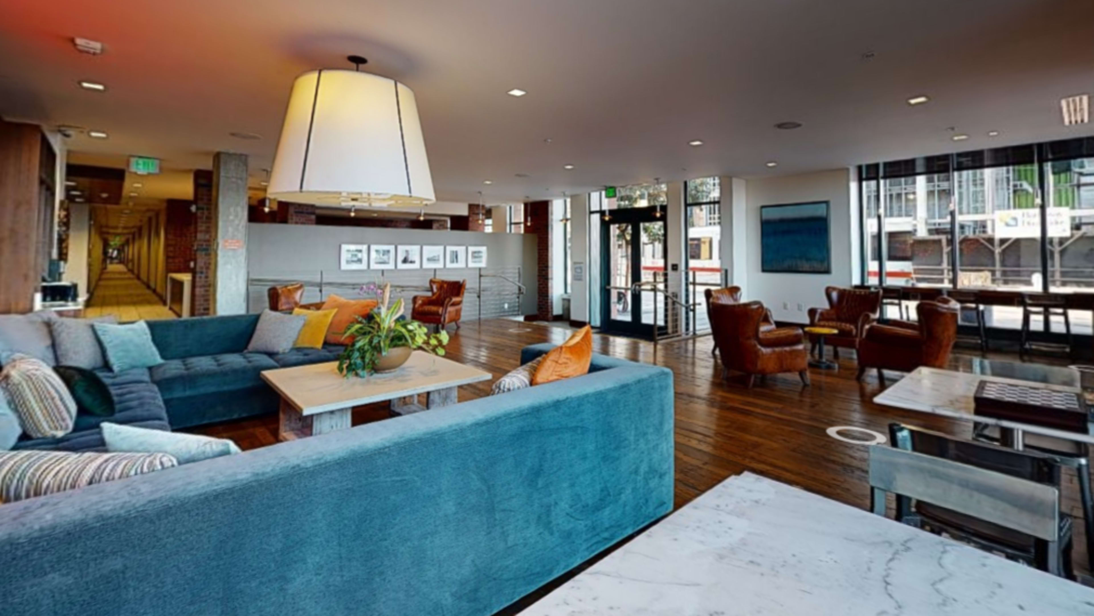 A spacious, modern lounge area featuring comfortable seating, large windows, and a mix of wood and soft furnishings.