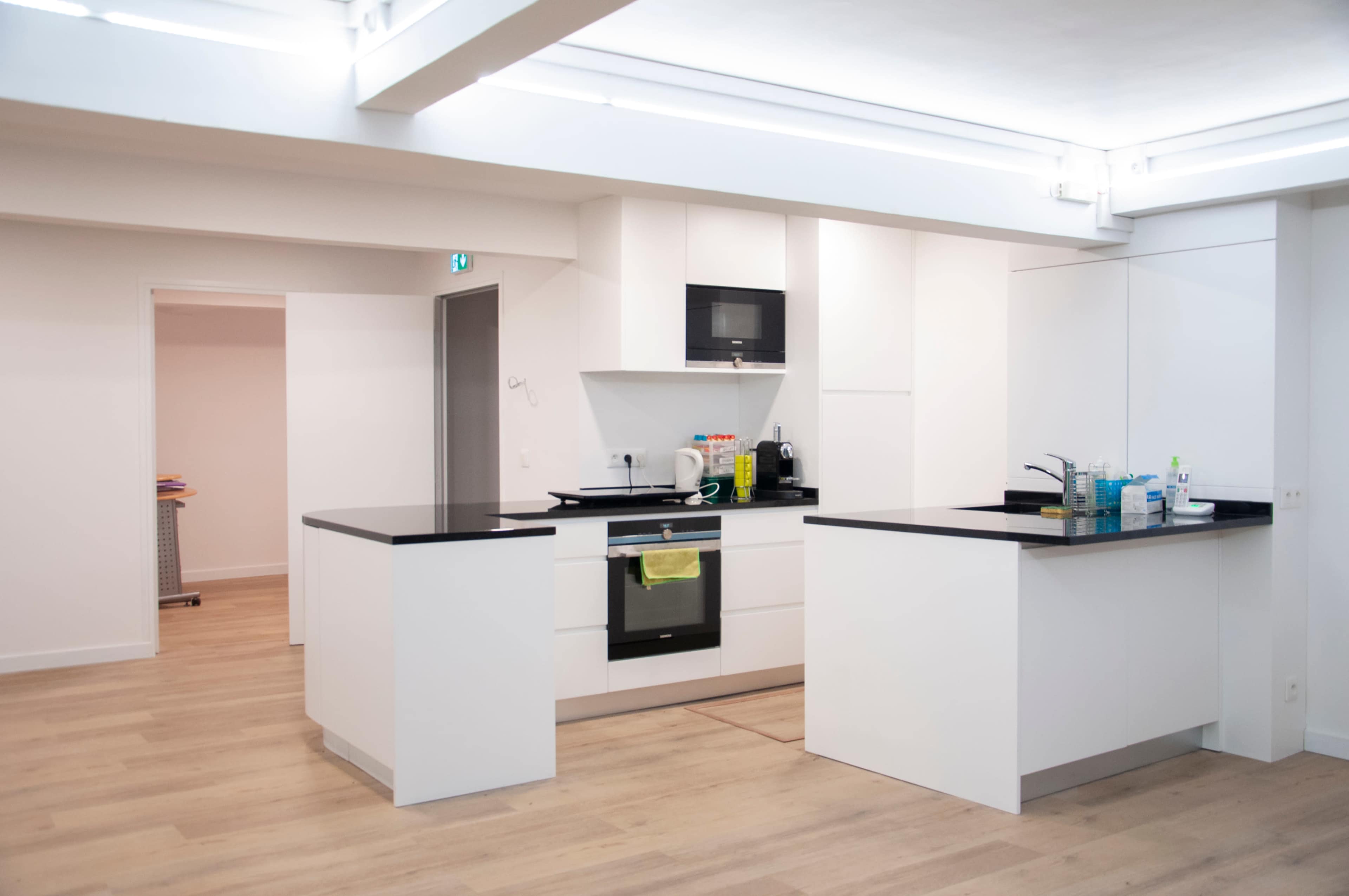 A modern kitchen with white cabinetry, a black countertop, and minimalistic design elements.