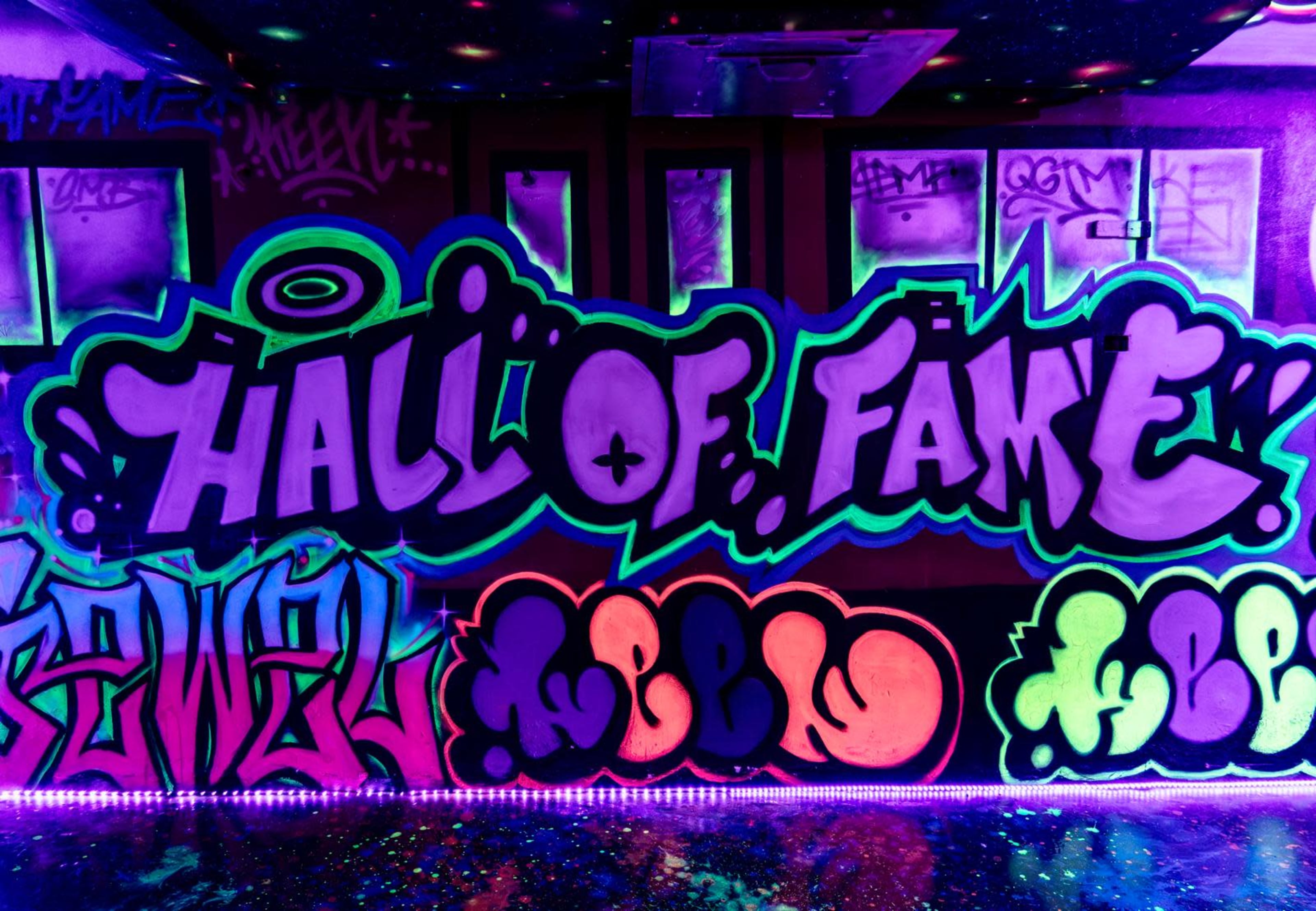 A brightly colored graffiti mural that reads "HALL OF FAKE" along with various other graffiti tags and designs.