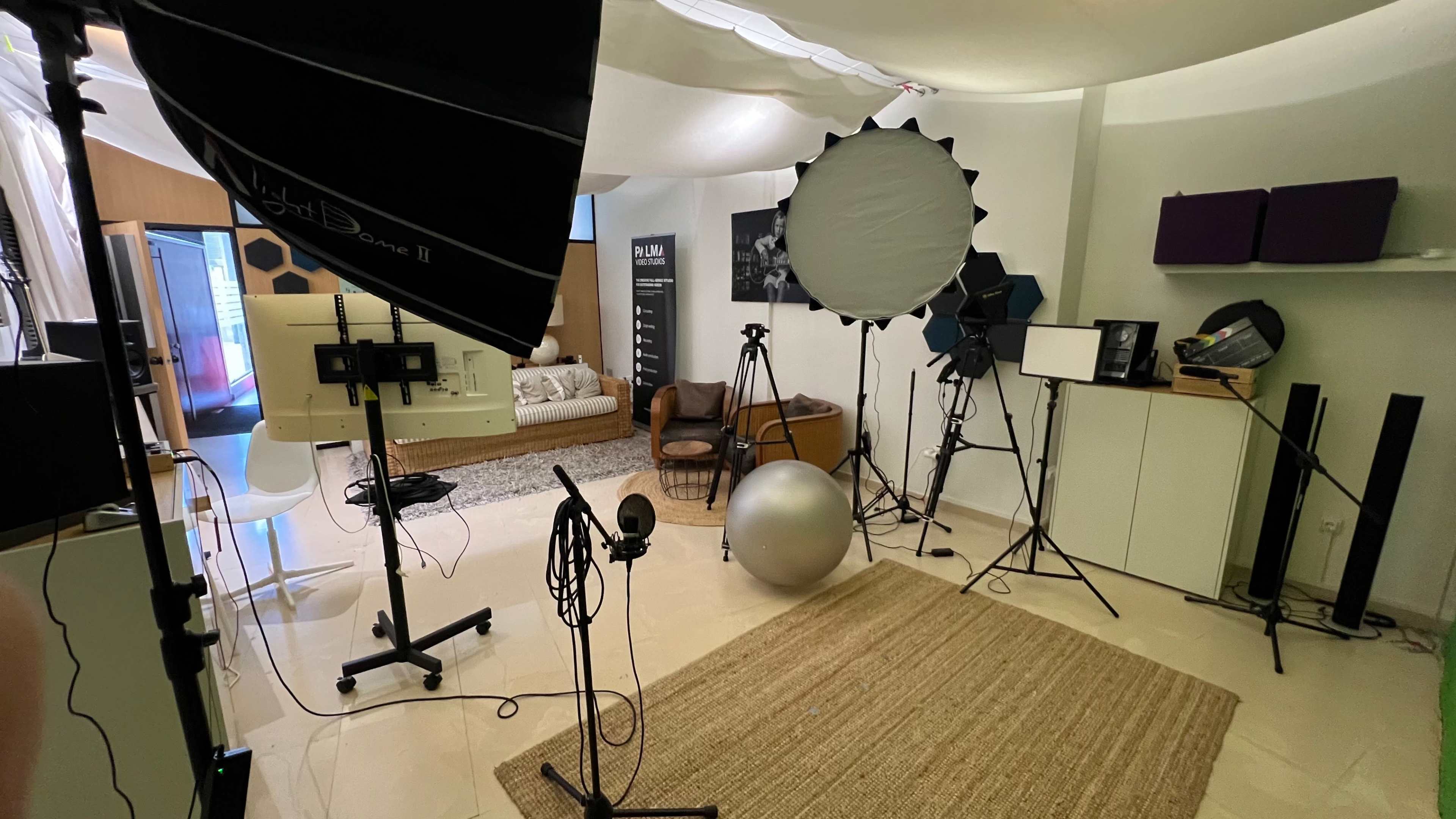 The image shows a photography studio equipped with lighting equipment, tripods, a backdrop, and various props arranged in a spacious room.