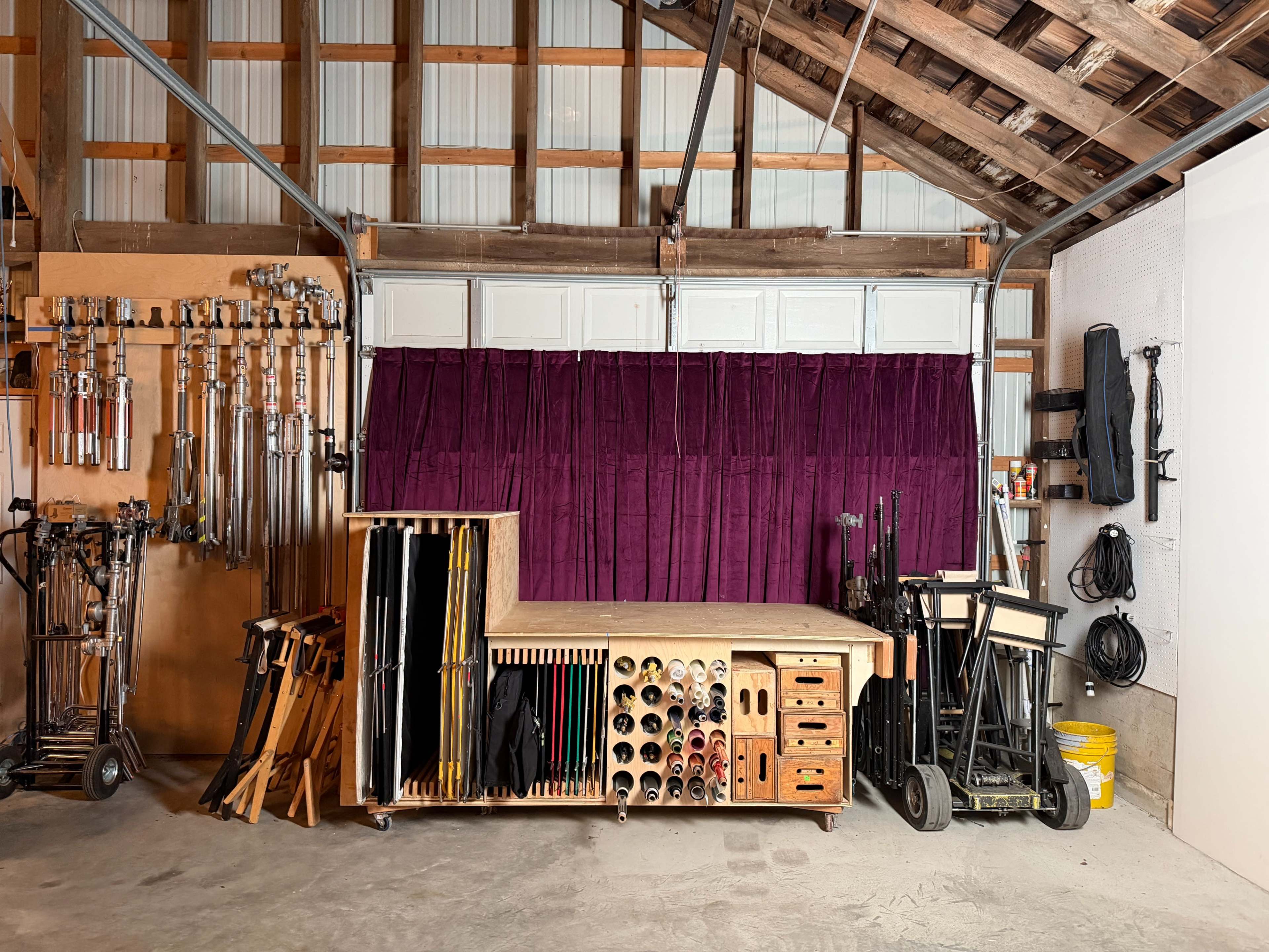 The image shows a well-organized workshop or studio space with various equipment, storage units, and a purple curtain at the back.