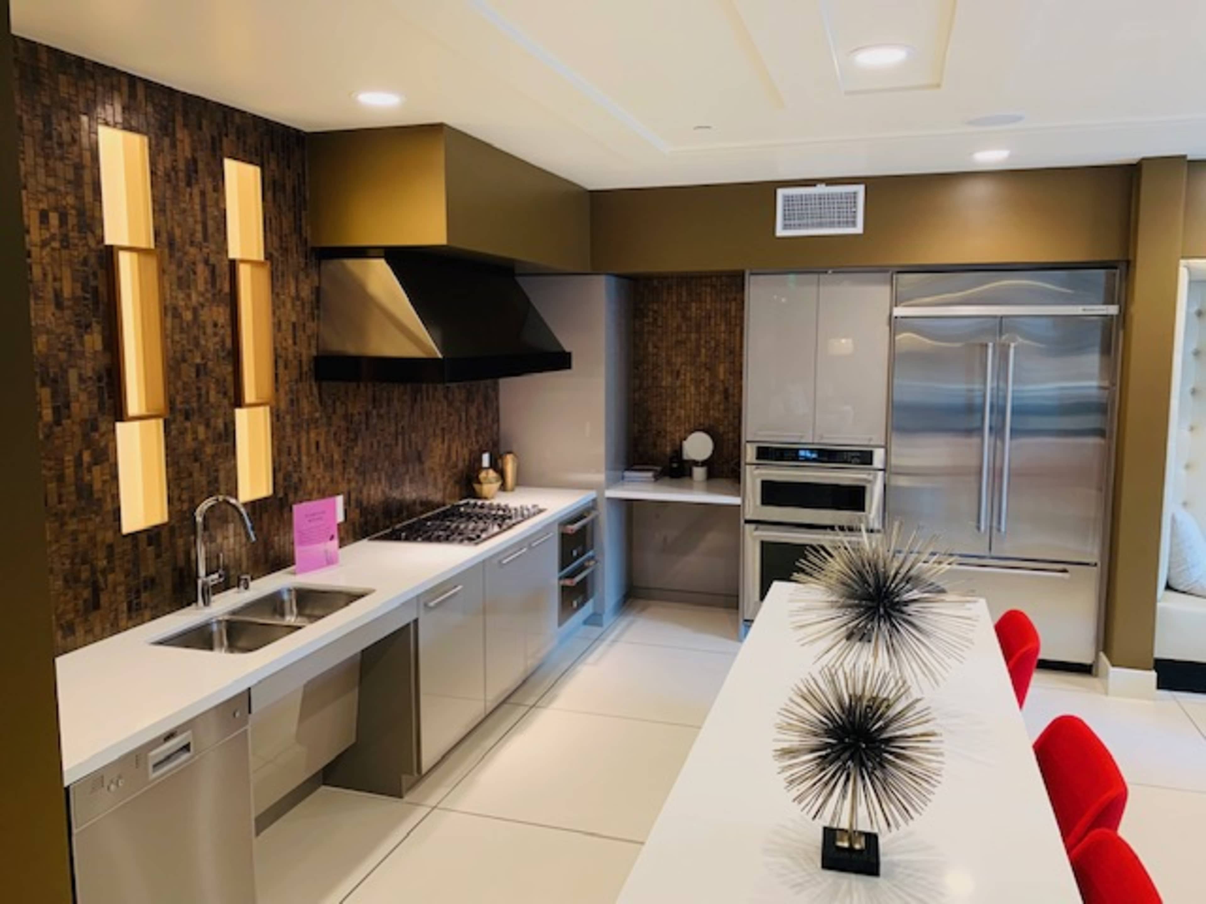 A modern kitchen featuring stainless steel appliances, sleek cabinetry, and a dining table with decorative centerpieces.