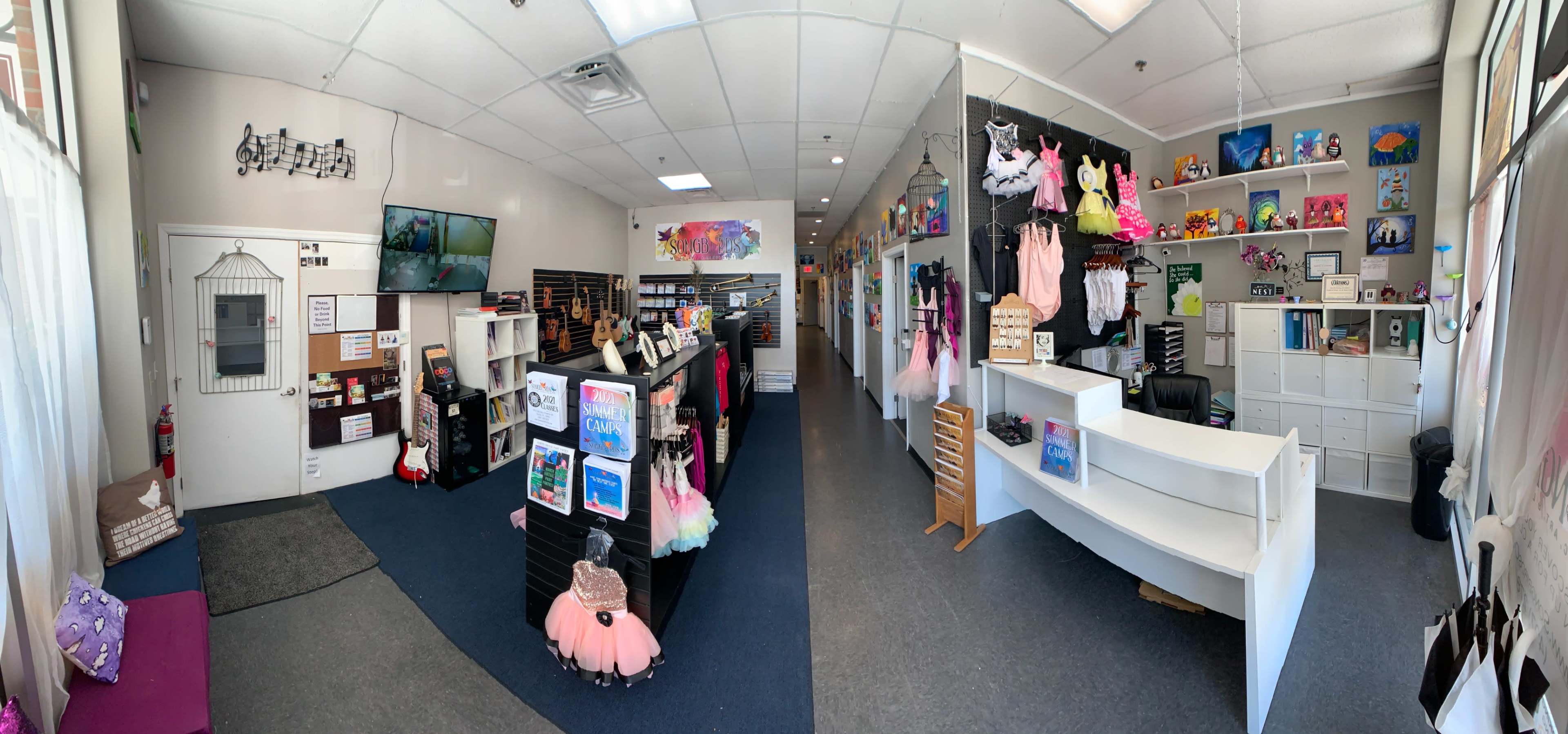 A spacious dance studio interior with display shelves, dance costumes, and a reception area.