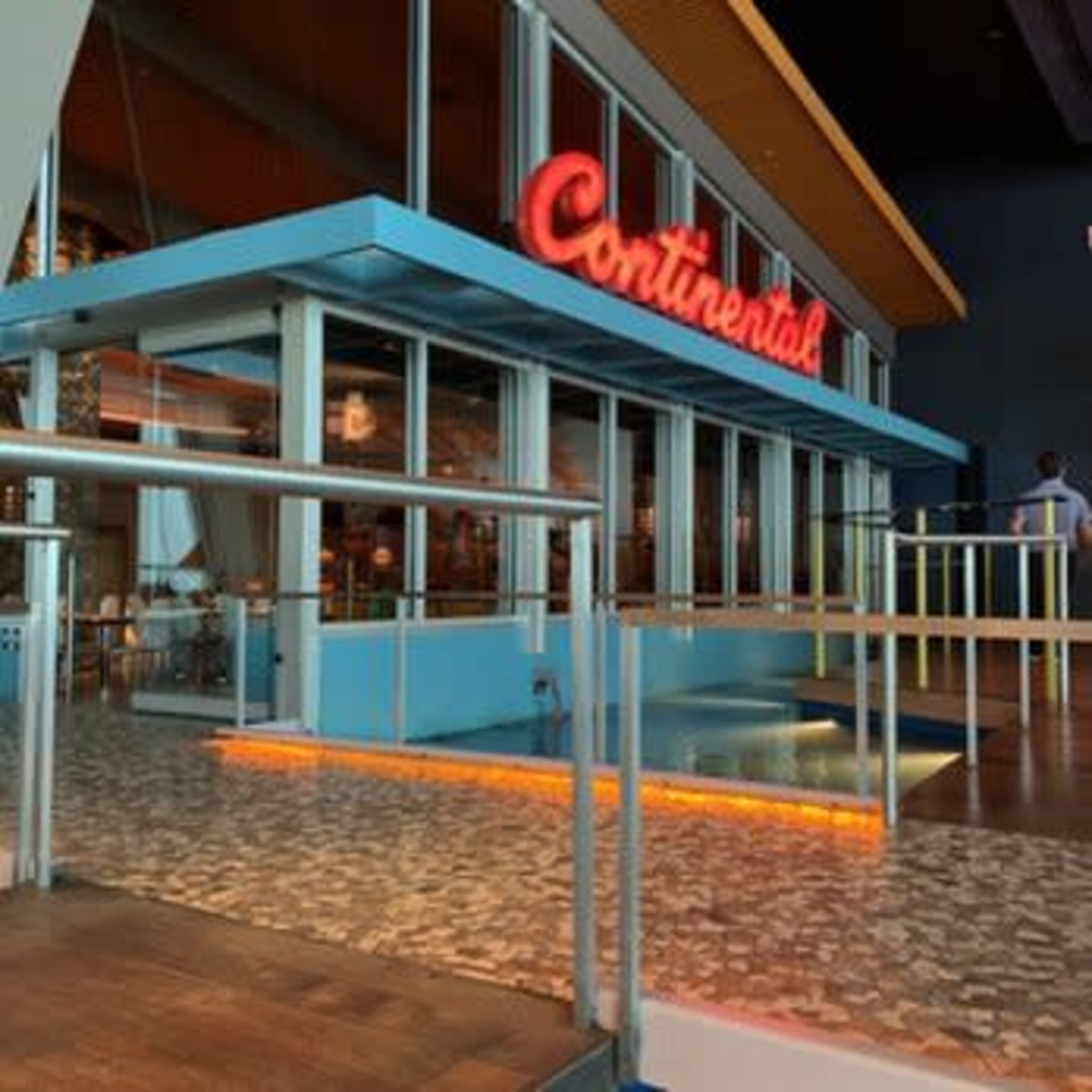 The exterior of a restaurant named "Continental," featuring a brightly lit sign and a ramp leading to the entrance.