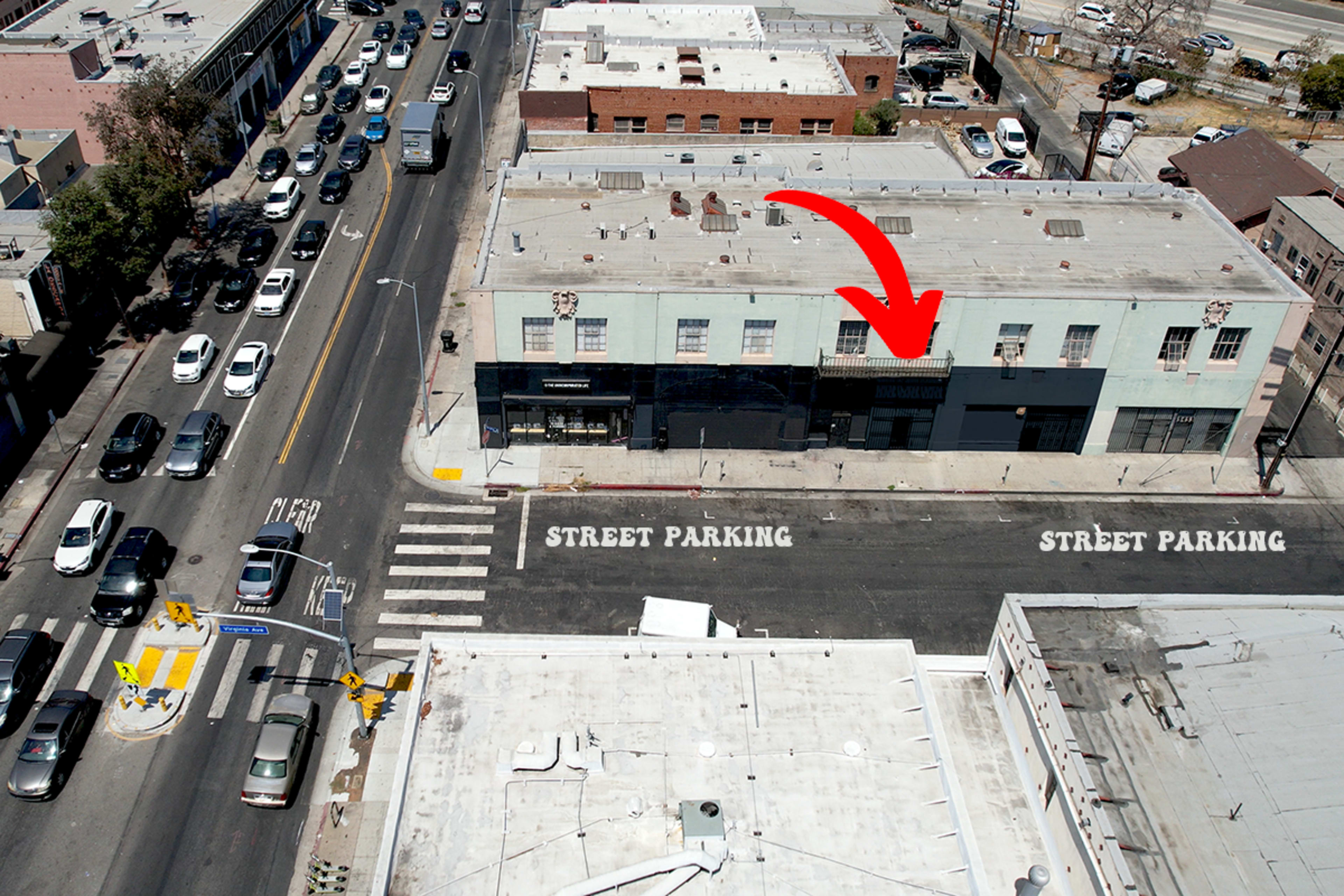 An aerial view shows a street with parked cars and a building with an arrow indicating a designated parking area.