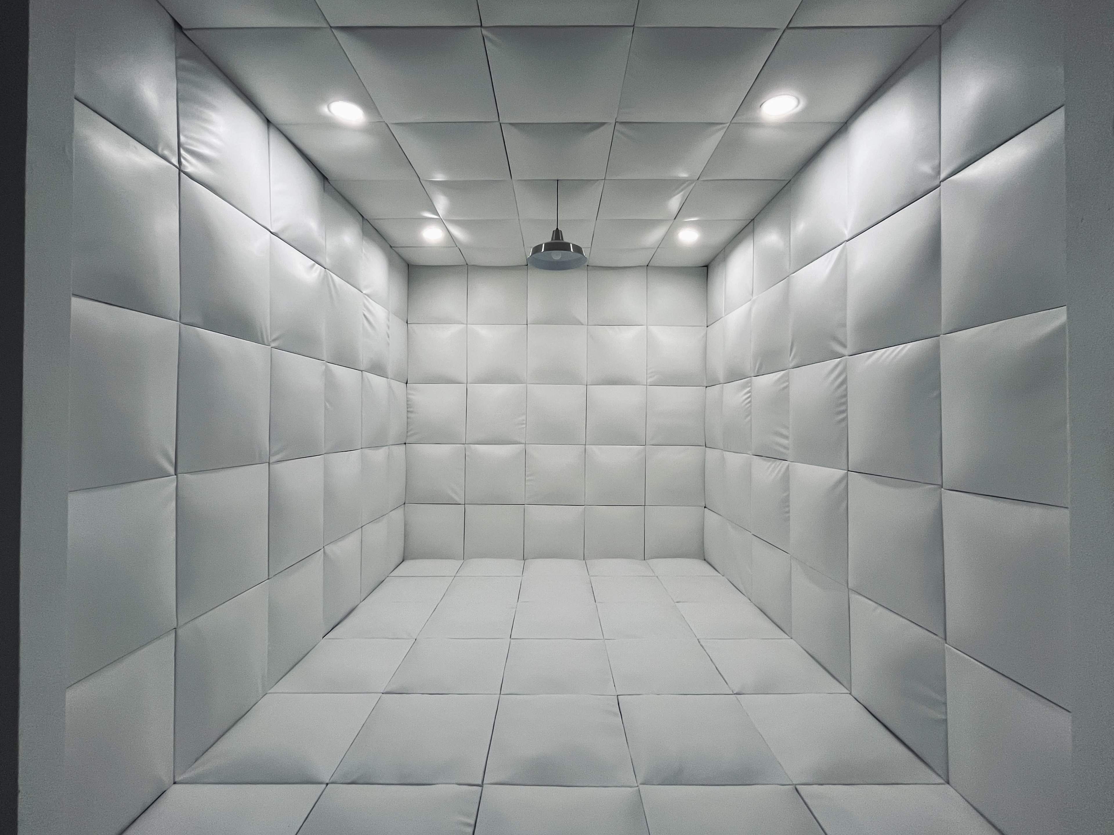 A padded, white room with smooth walls and a central ceiling light.
