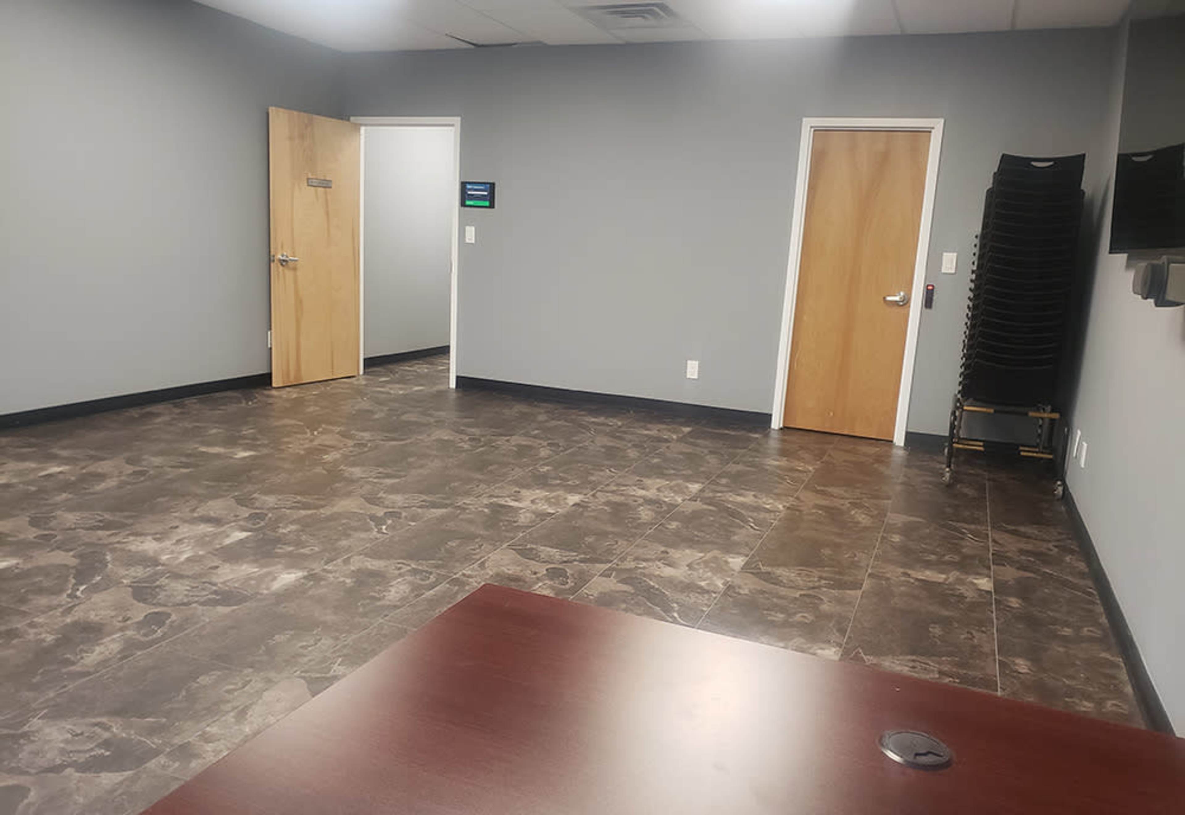 An empty room with gray walls, tiled flooring, and two doors, one of which is slightly ajar.