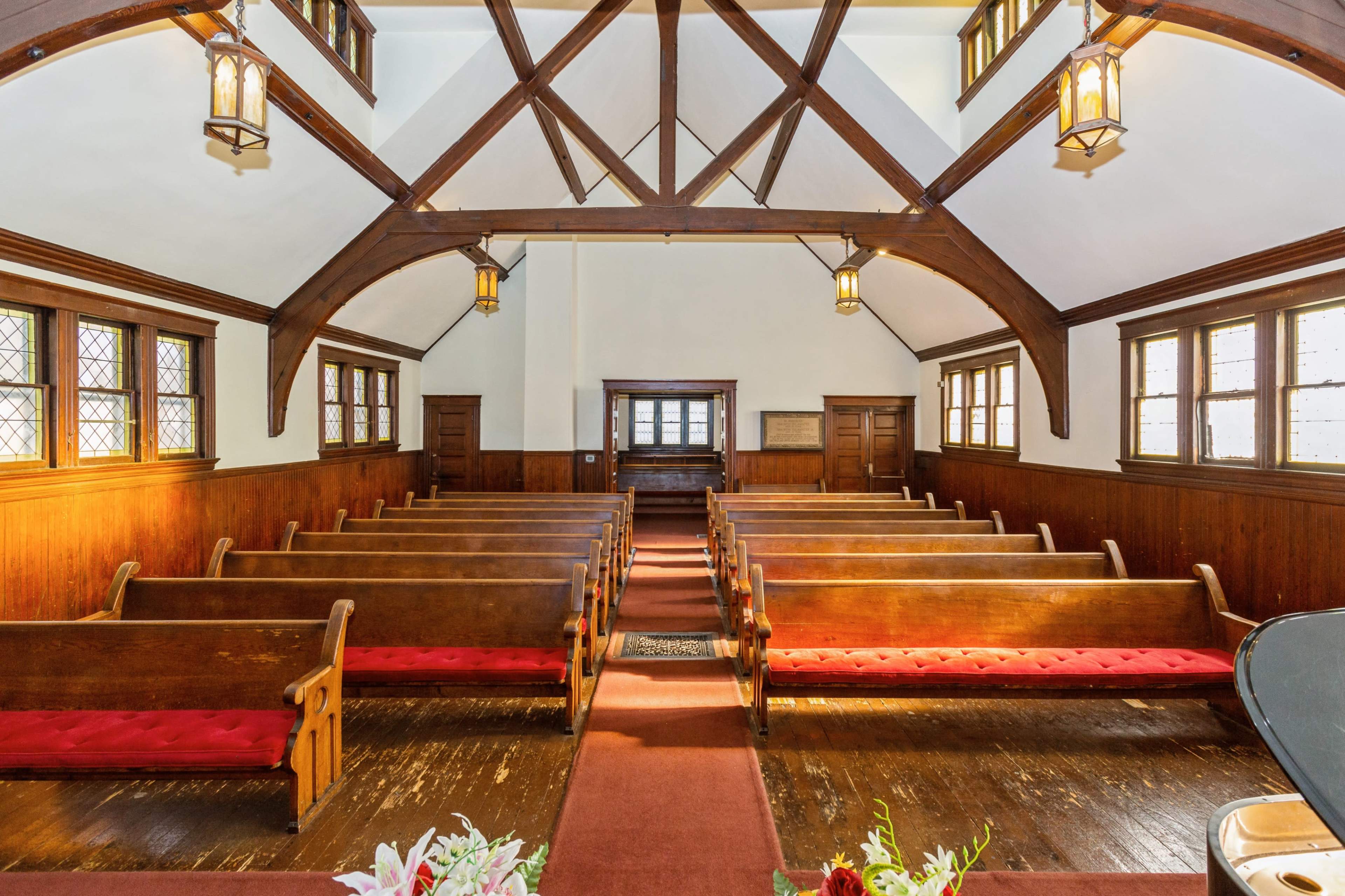 The interior of a church with wooden pews arranged in rows, vaulted ceilings, and large windows allowing light to enter.