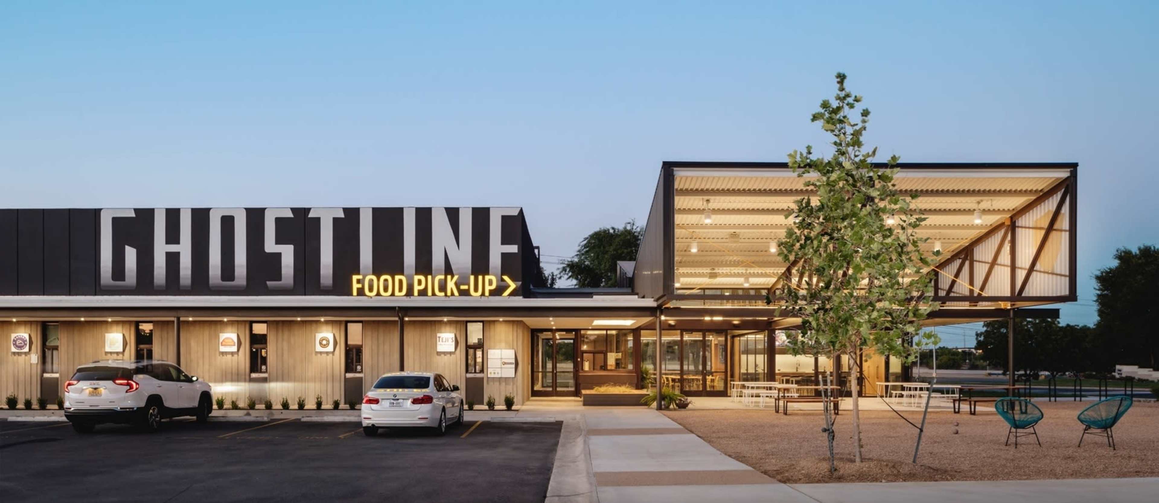The image shows a modern food pickup establishment called "Ghostline," featuring an outdoor seating area and a distinct architectural design with illuminated signage.