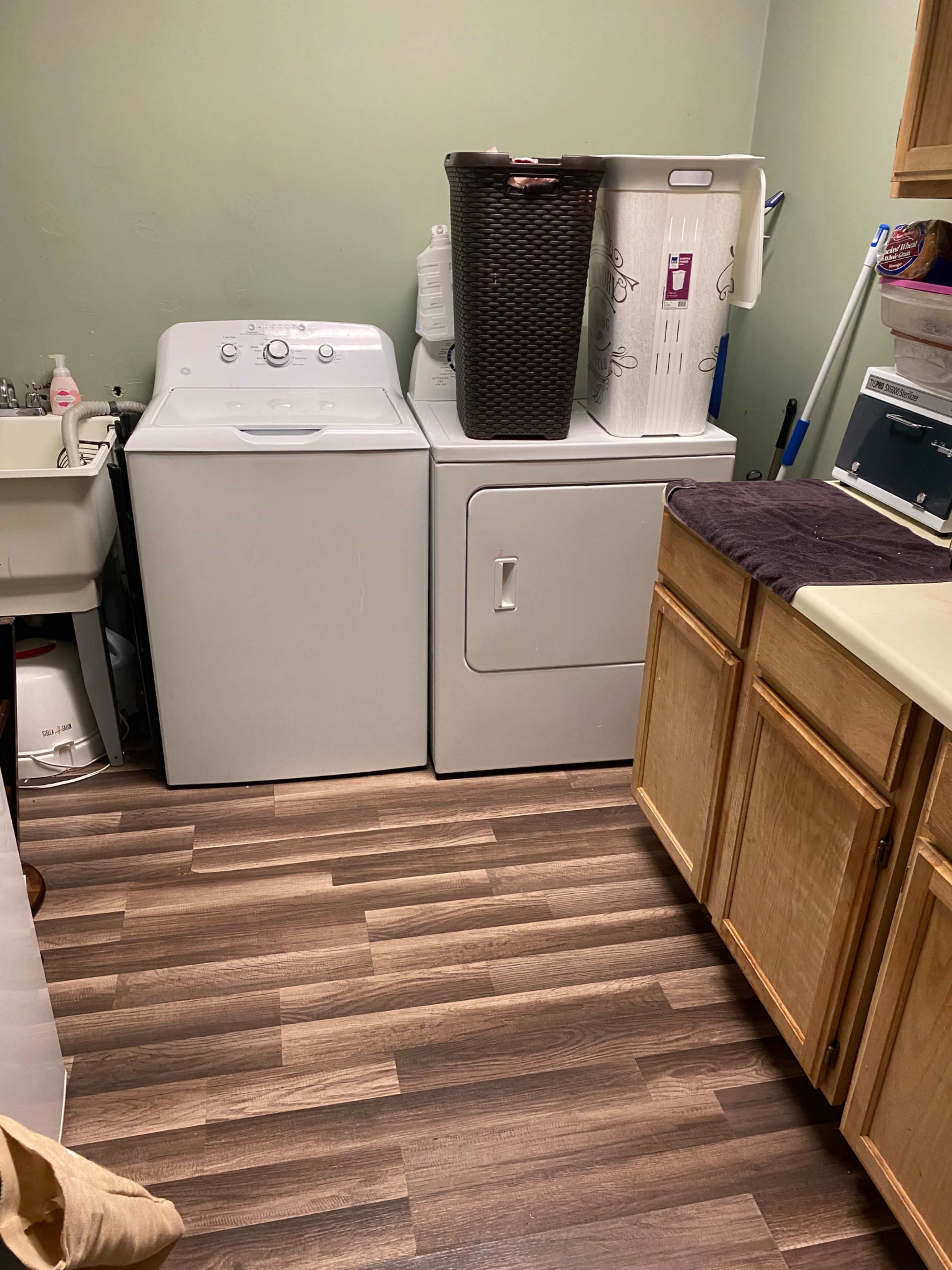 A laundry room with a washing machine, dryer, and a laundry basket on a countertop.