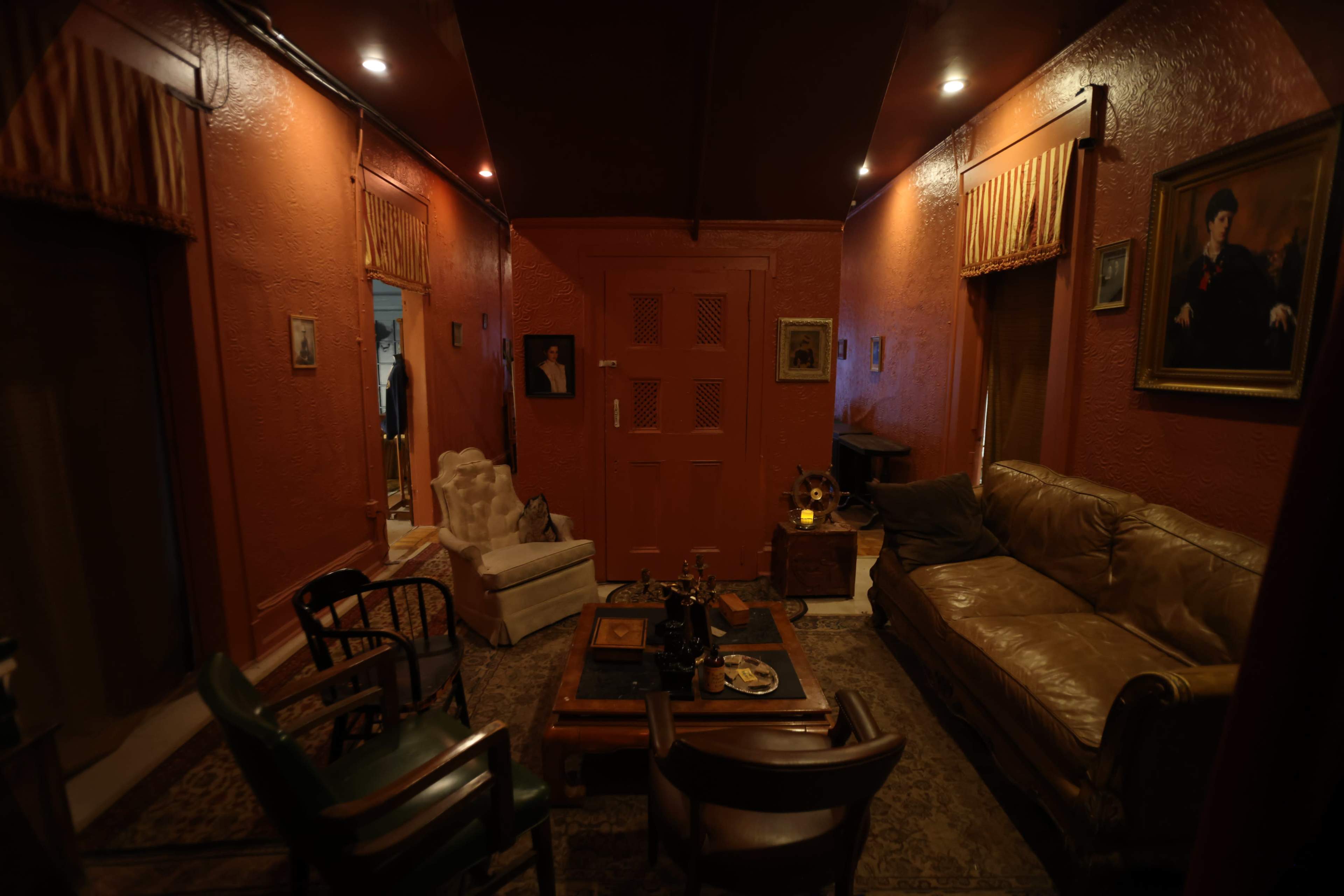 The room features two sofas, a coffee table, and various pieces of art on the walls, all set against red-painted walls.