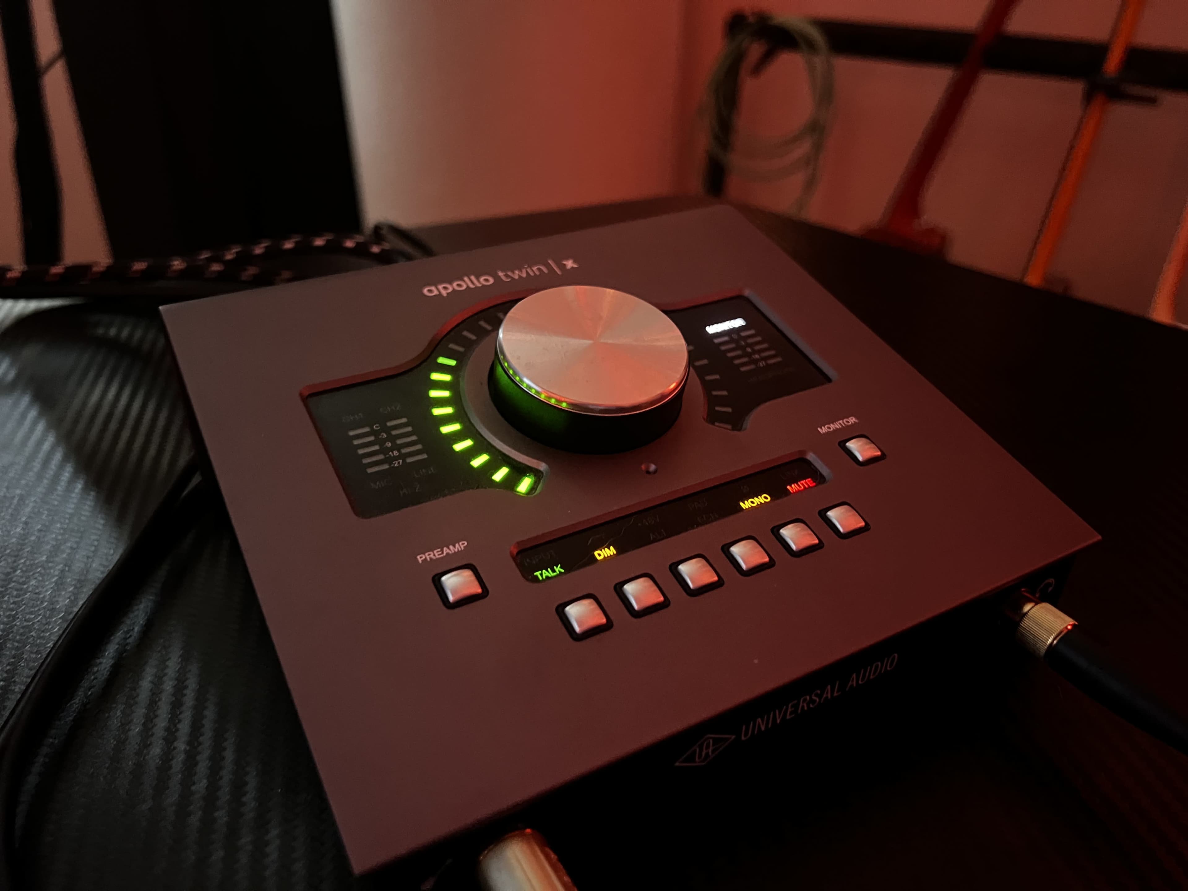 The image shows a Universal Audio Apollo Twin X audio interface with illuminated controls and a large central knob.