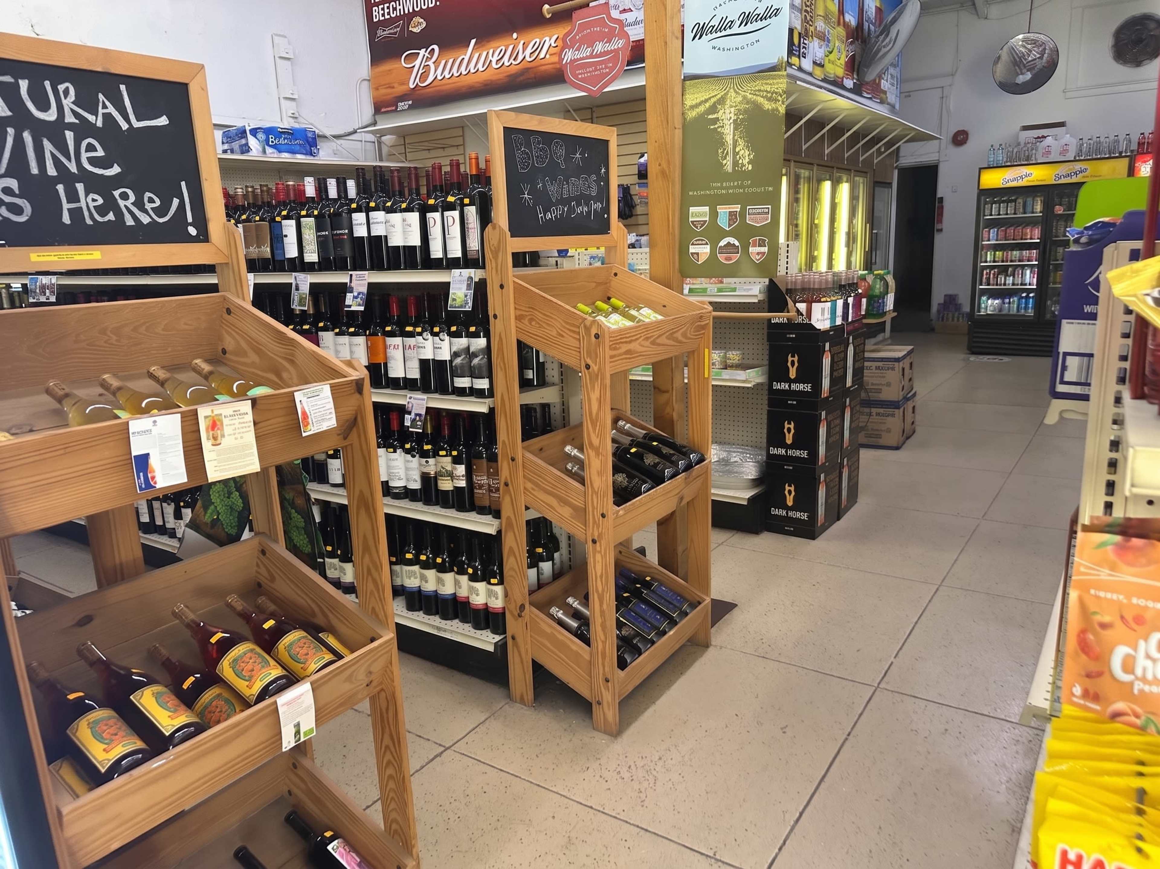 The image shows an interior of a retail store featuring wine racks, refrigerated beverage displays, and various products organized on shelves.