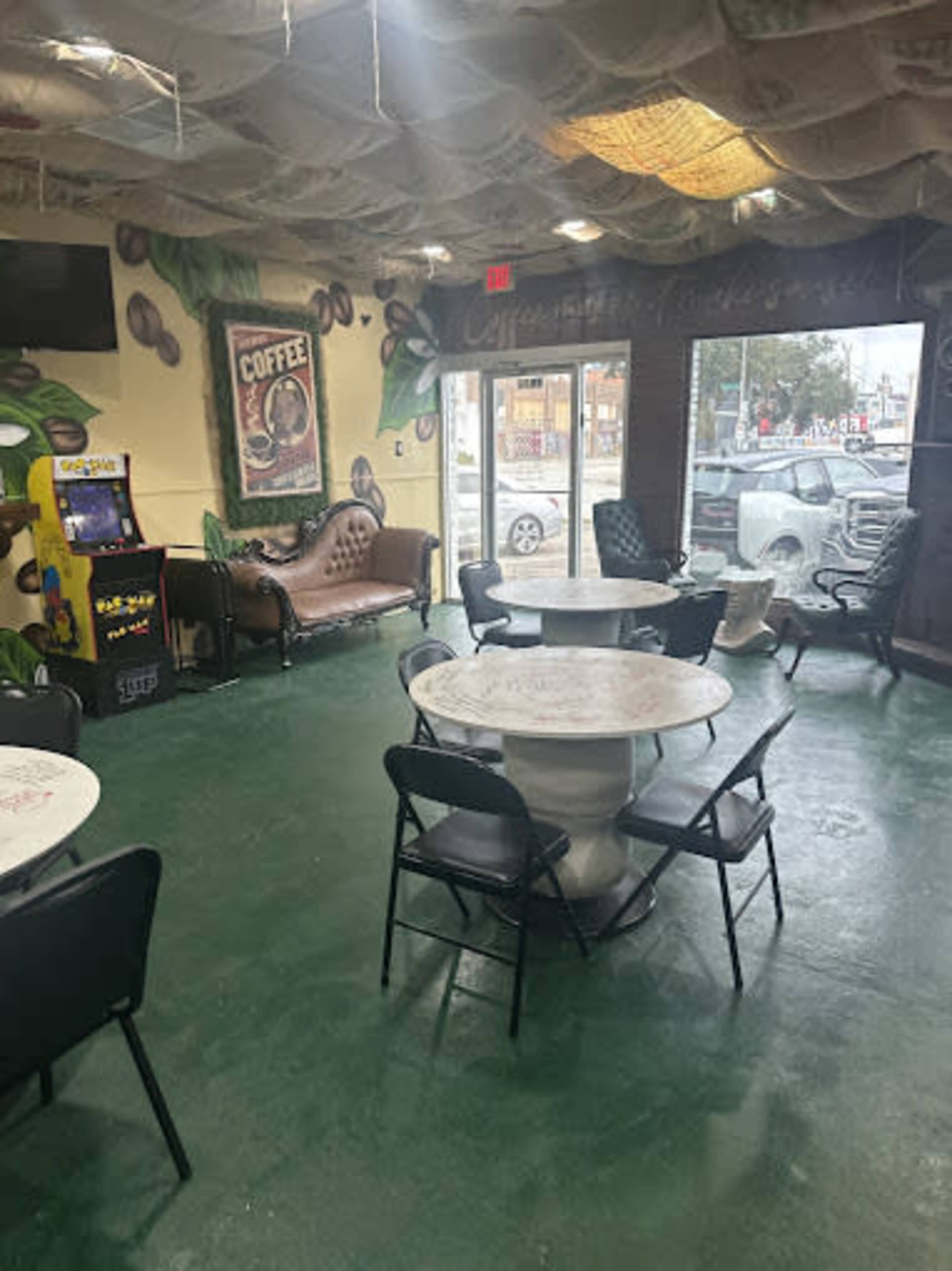 The image shows a cozy coffee shop interior with tables and chairs, a vintage couch, and coffee-themed wall art.