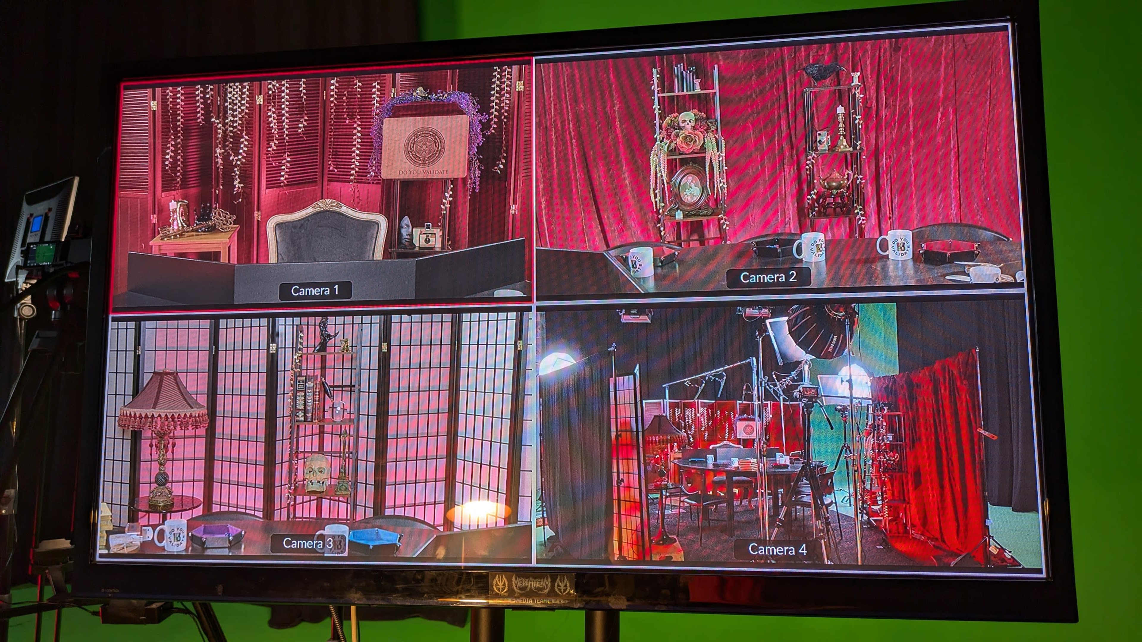 A monitor displays four camera feeds from a studio setup, showing various angles of decorated backgrounds and equipment.