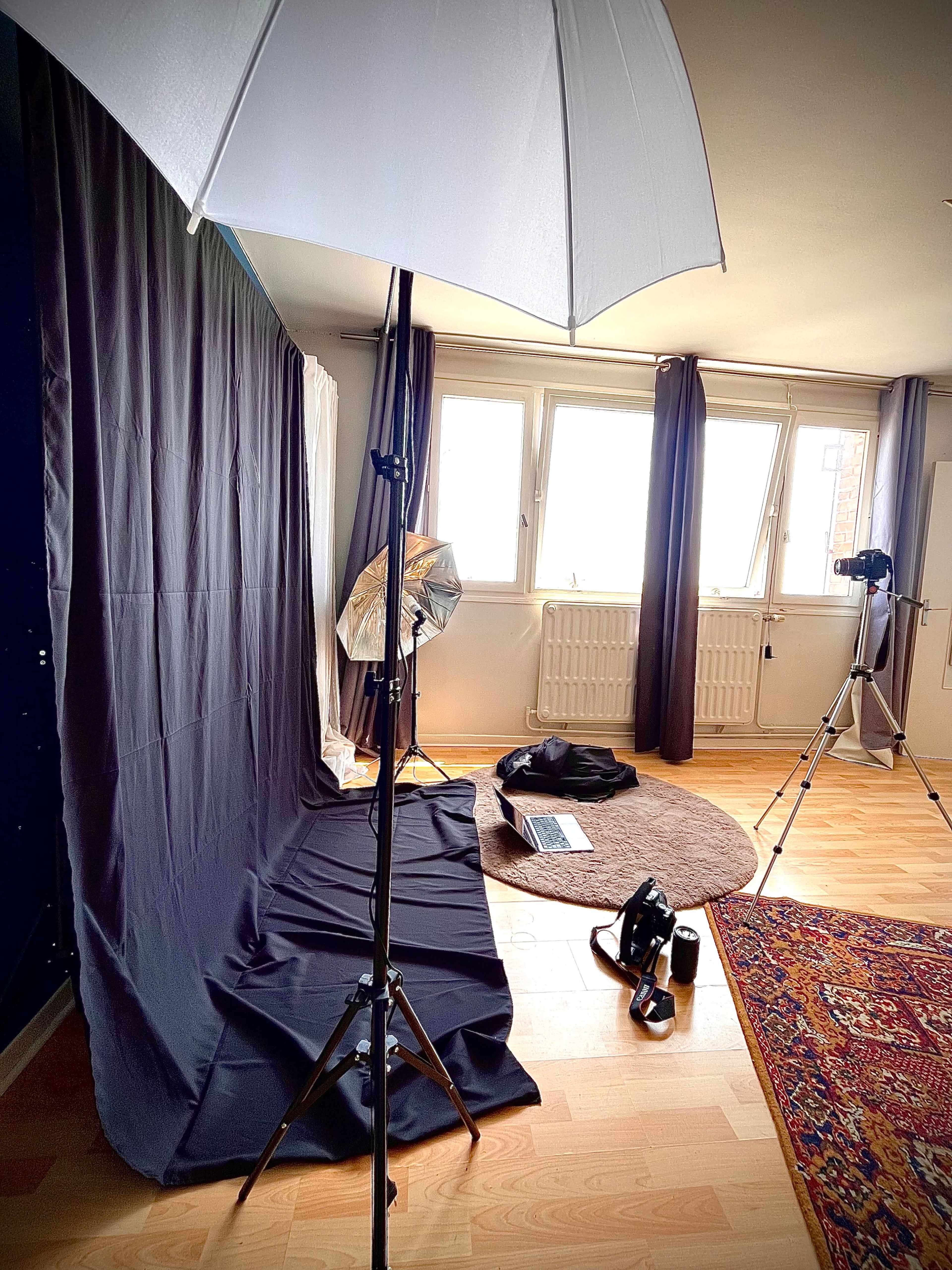 The image shows a photography studio setup with a backdrop, lighting equipment, and a camera positioned on a tripod.