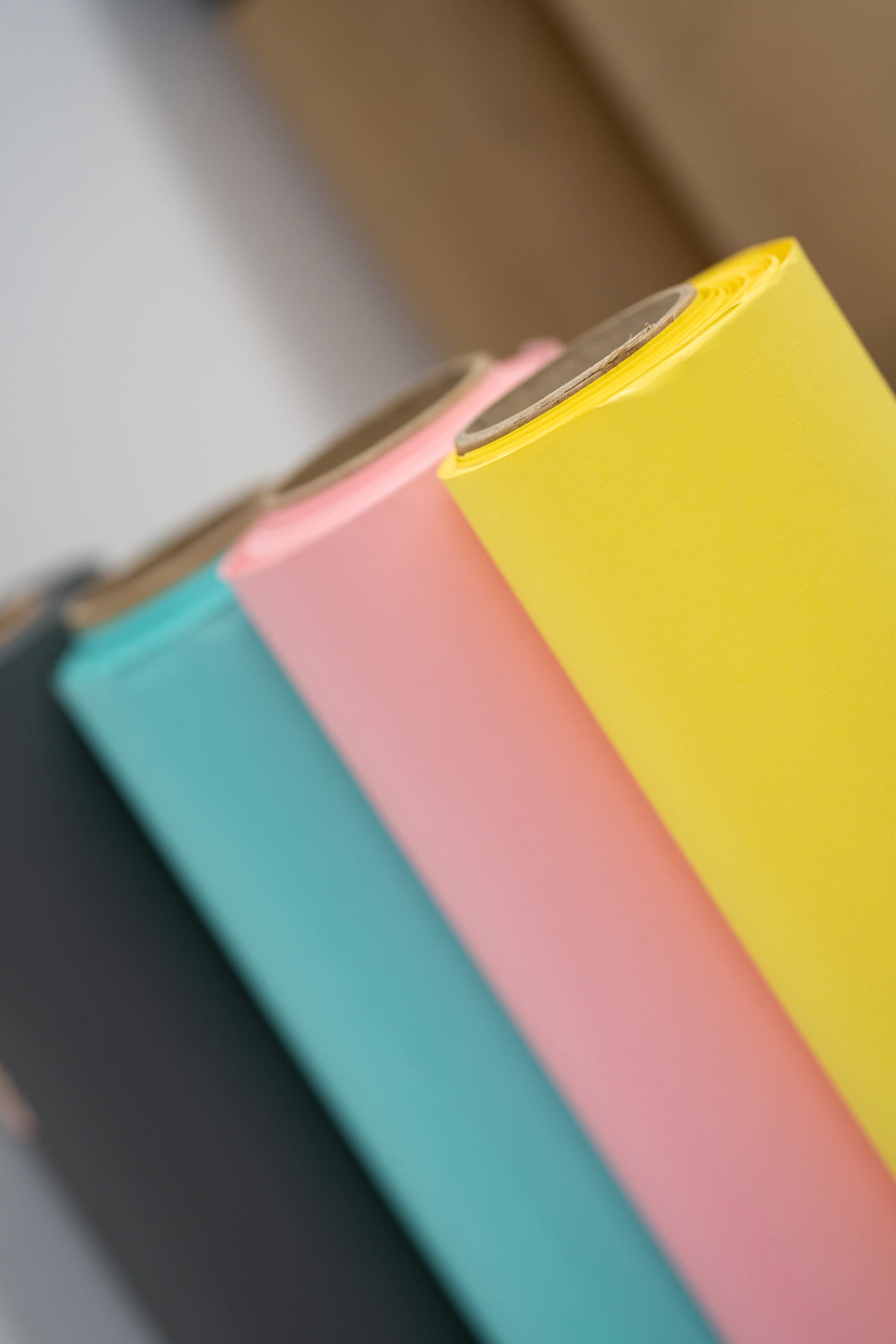 A stack of rolls of colored paper in blue, pink, yellow, and black.