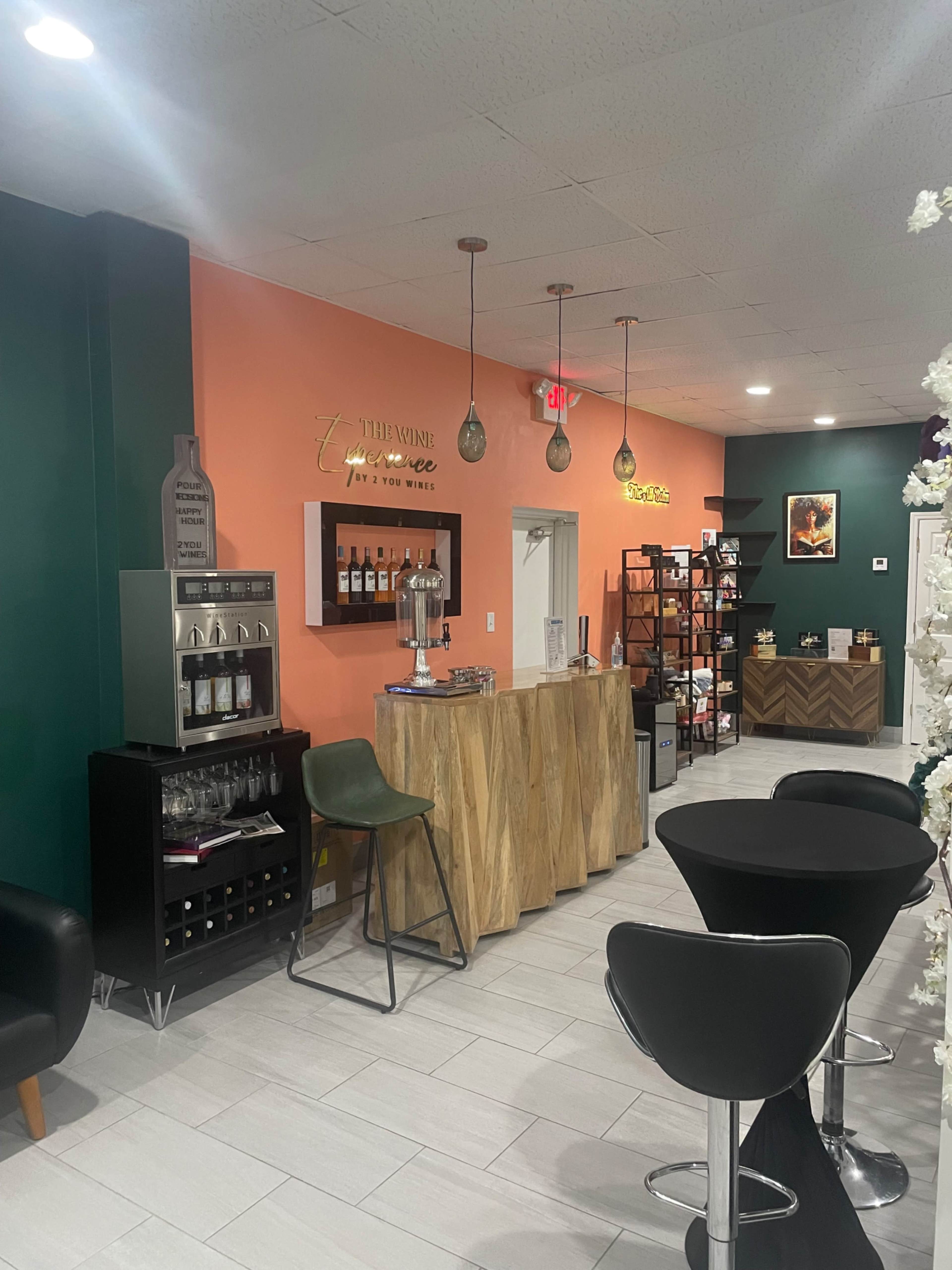 The image shows a modern wine tasting space featuring an orange and teal color scheme, wooden furniture, and wine shelves along the walls.
