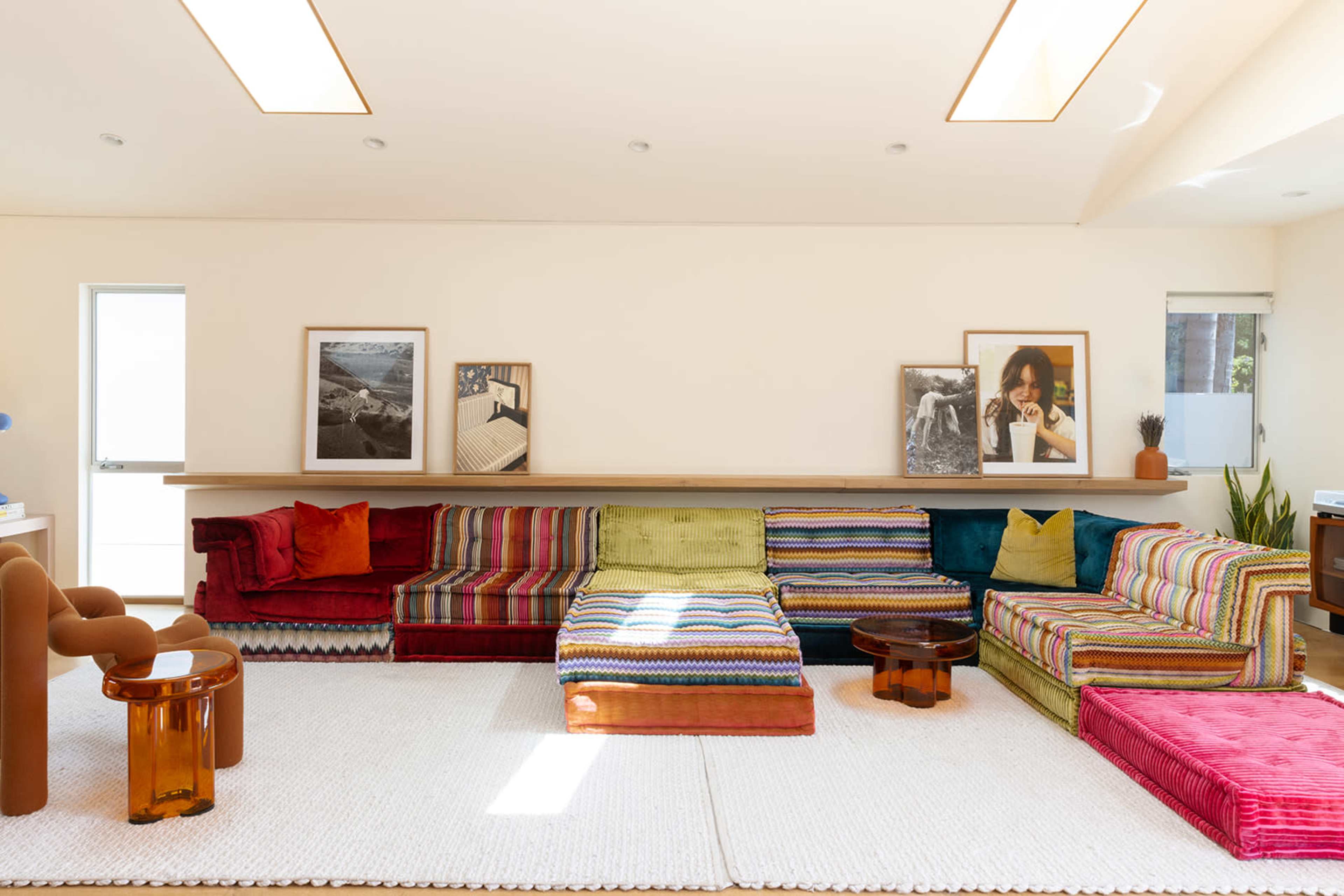 The room features a spacious seating area with a multi-colored sectional sofa and two framed photographs on the walls.