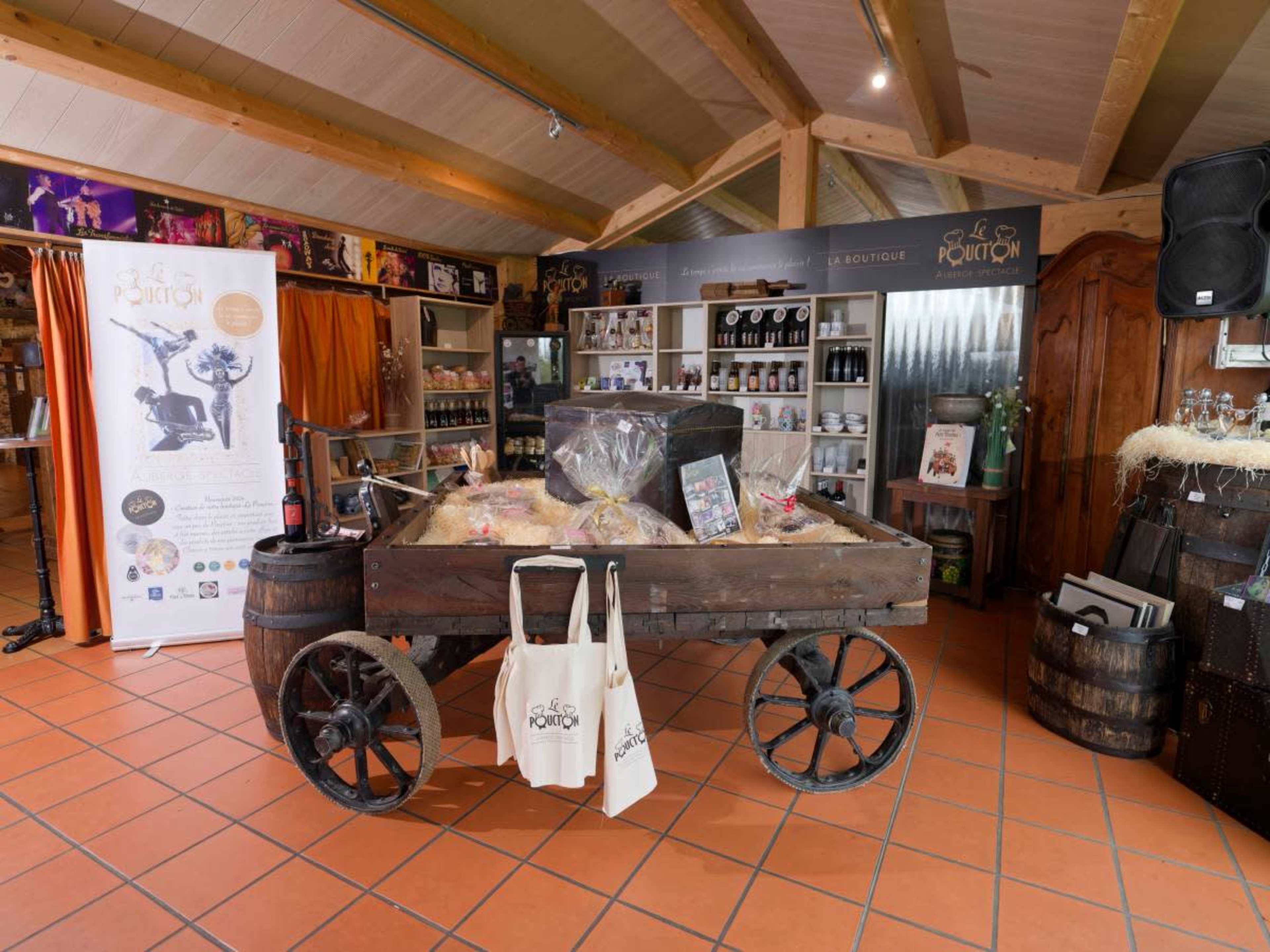 The image shows a rustic wooden cart filled with products, set against a backdrop of shelves displaying various goods in a store with a warm, inviting interior.