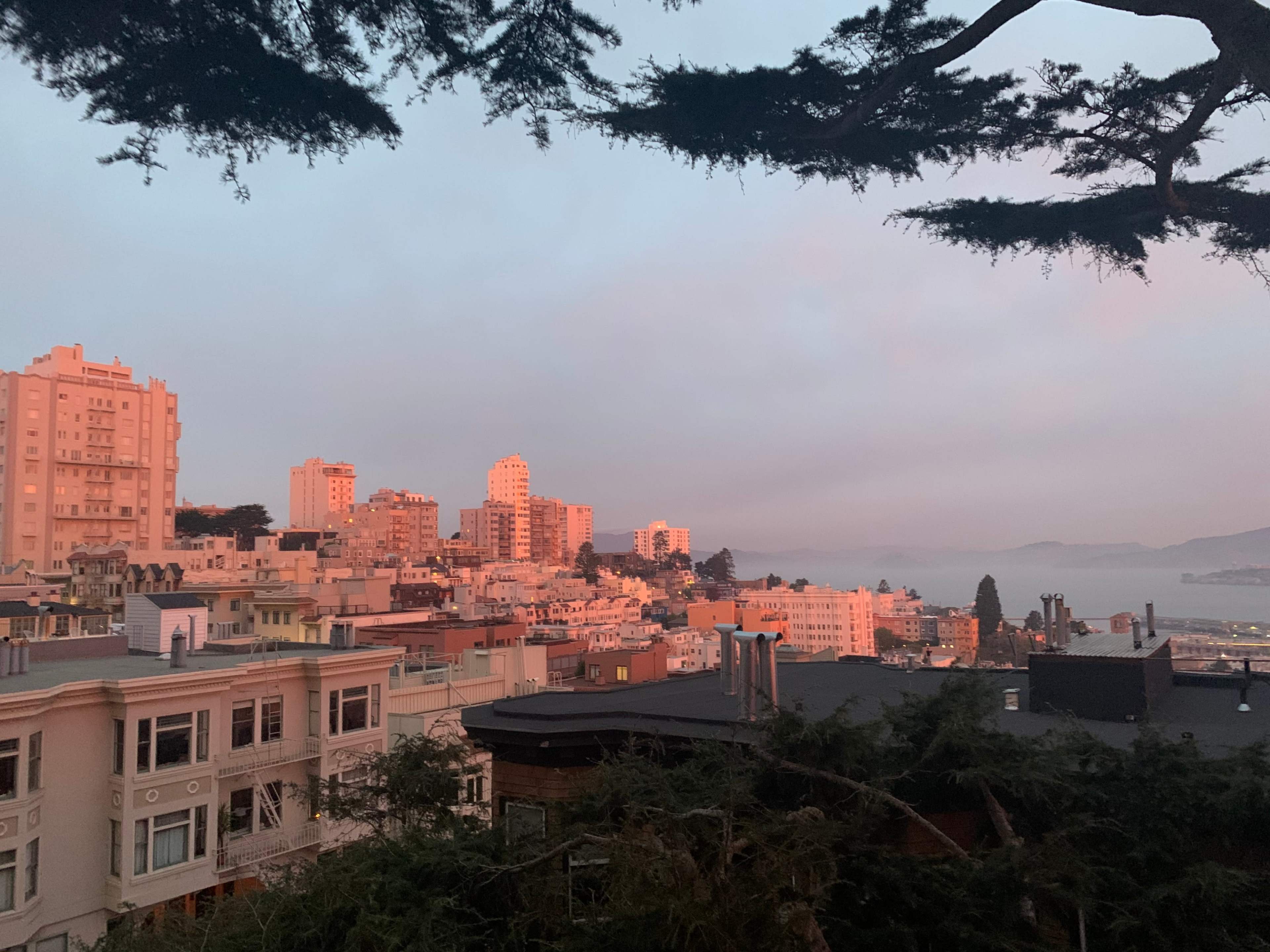 A view of a city skyline at sunset, with buildings and a body of water visible in the background.