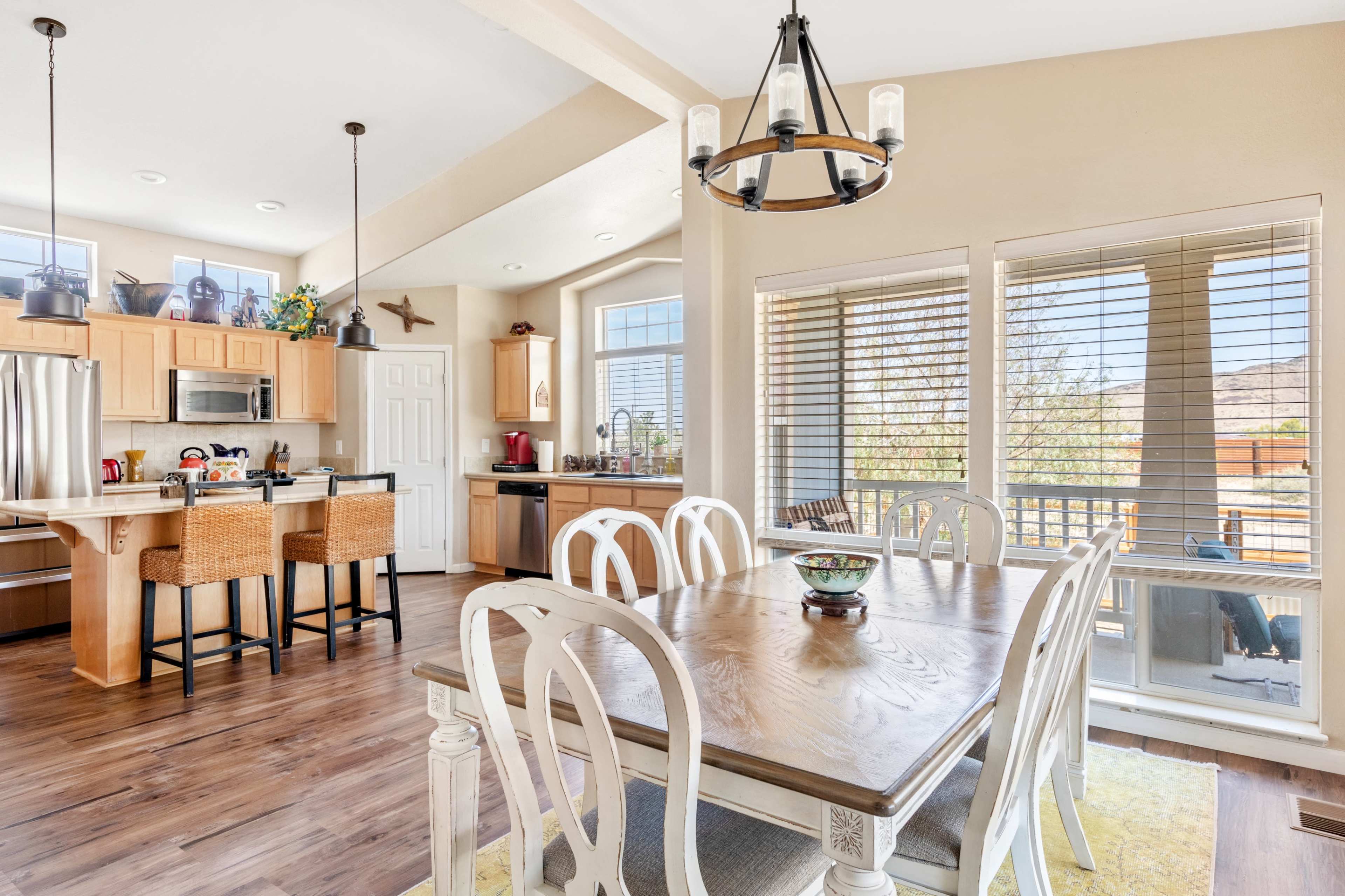 A bright, open-concept kitchen and dining area with wooden furnishings, a dining table, and large windows.