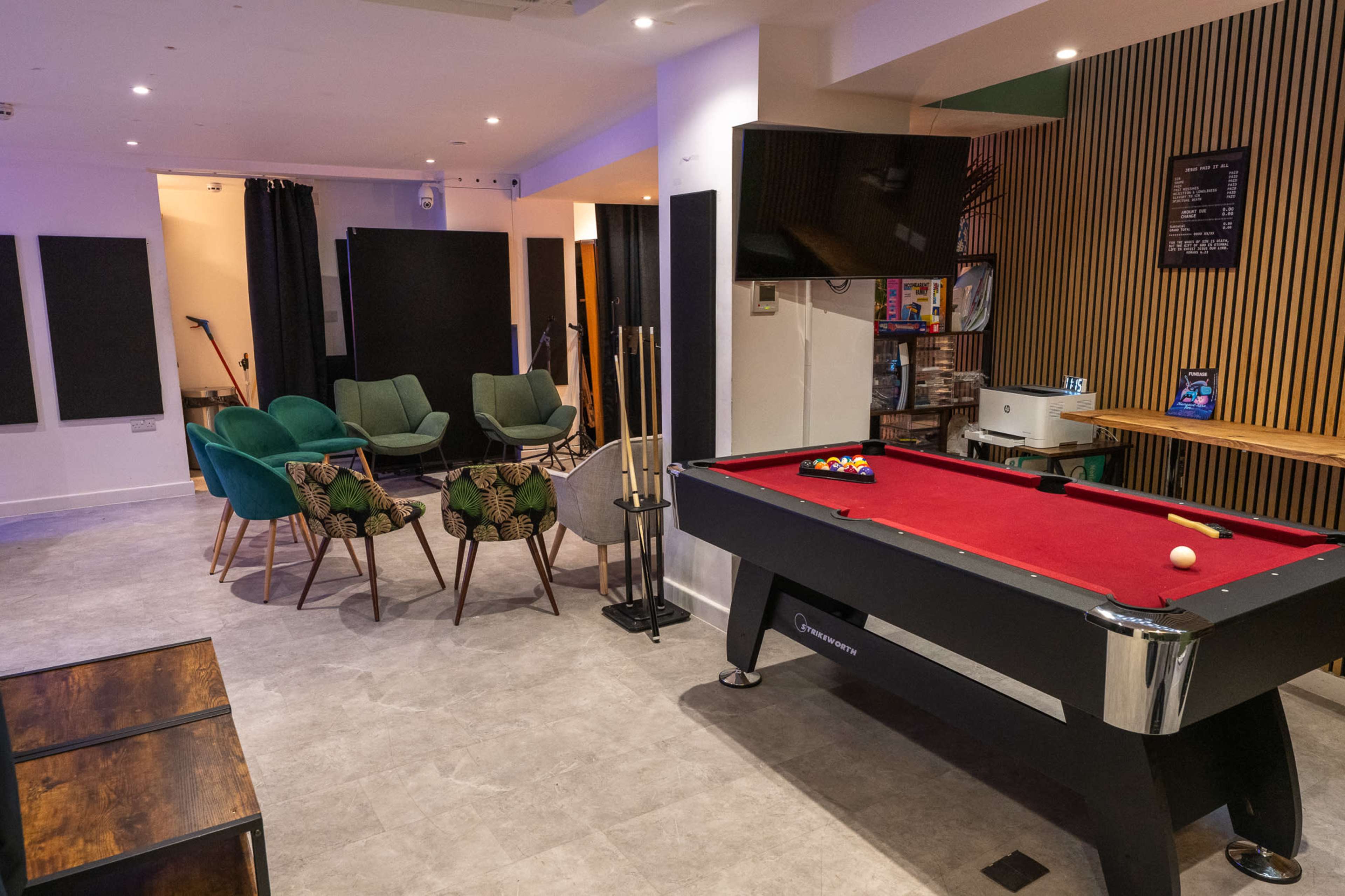 The scene features a lounge area with a pool table, surrounded by chairs and decorative accents, against a backdrop of modern decor.