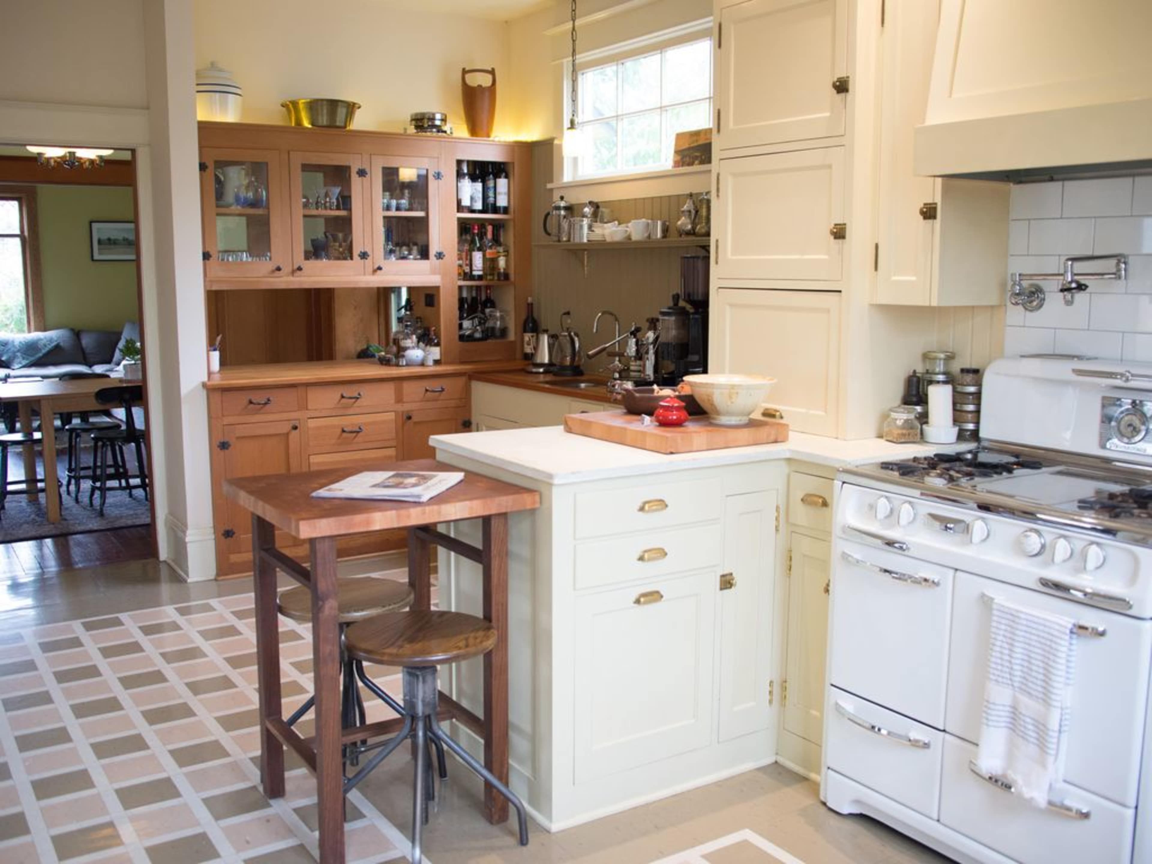 A cozy kitchen featuring a white stove, wooden cabinetry, a counter with a bowl, and a tiled floor.