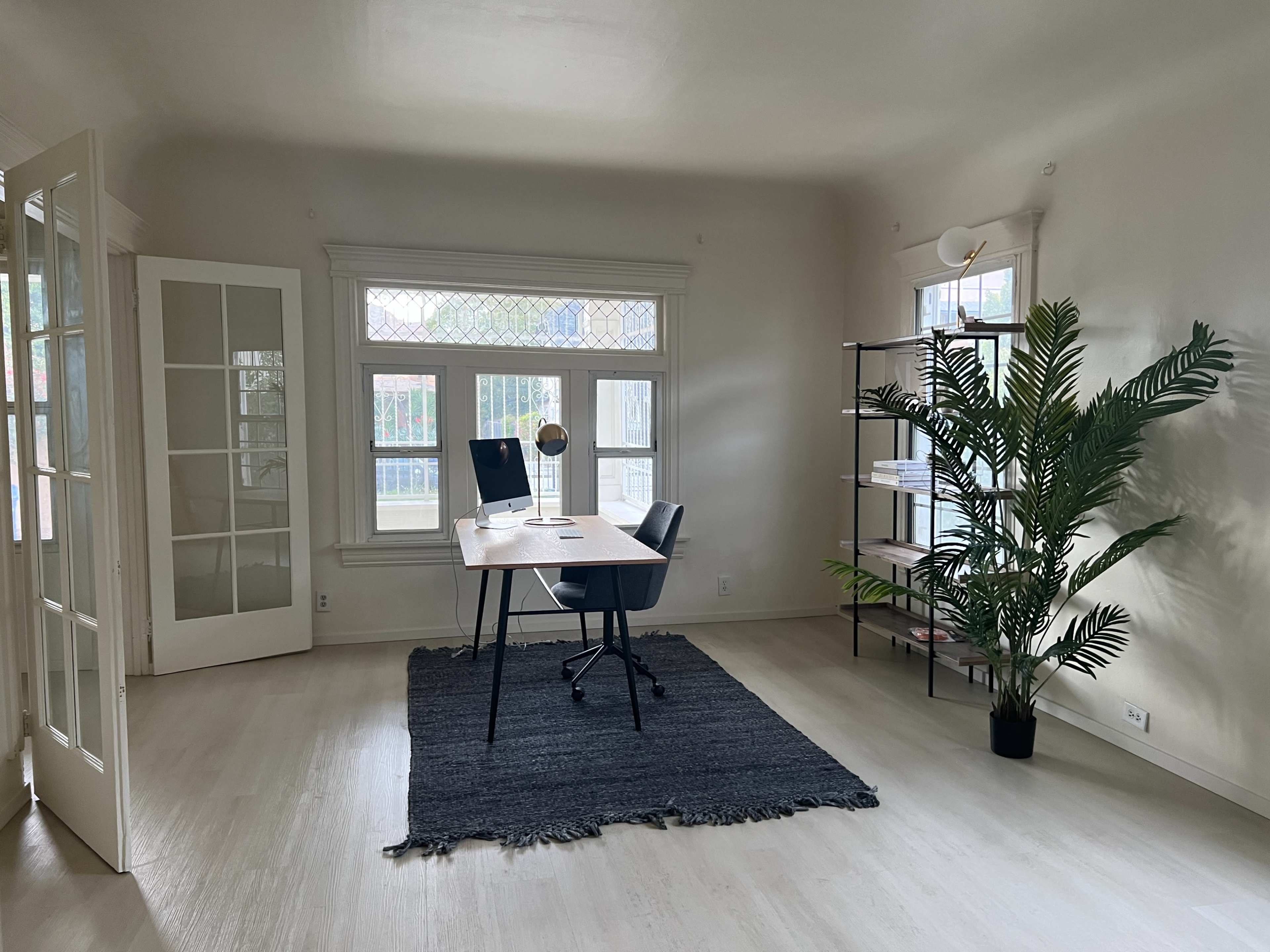 A minimalist office space features a desk with a chair, a globe, a plant, and large windows allowing natural light to enter.