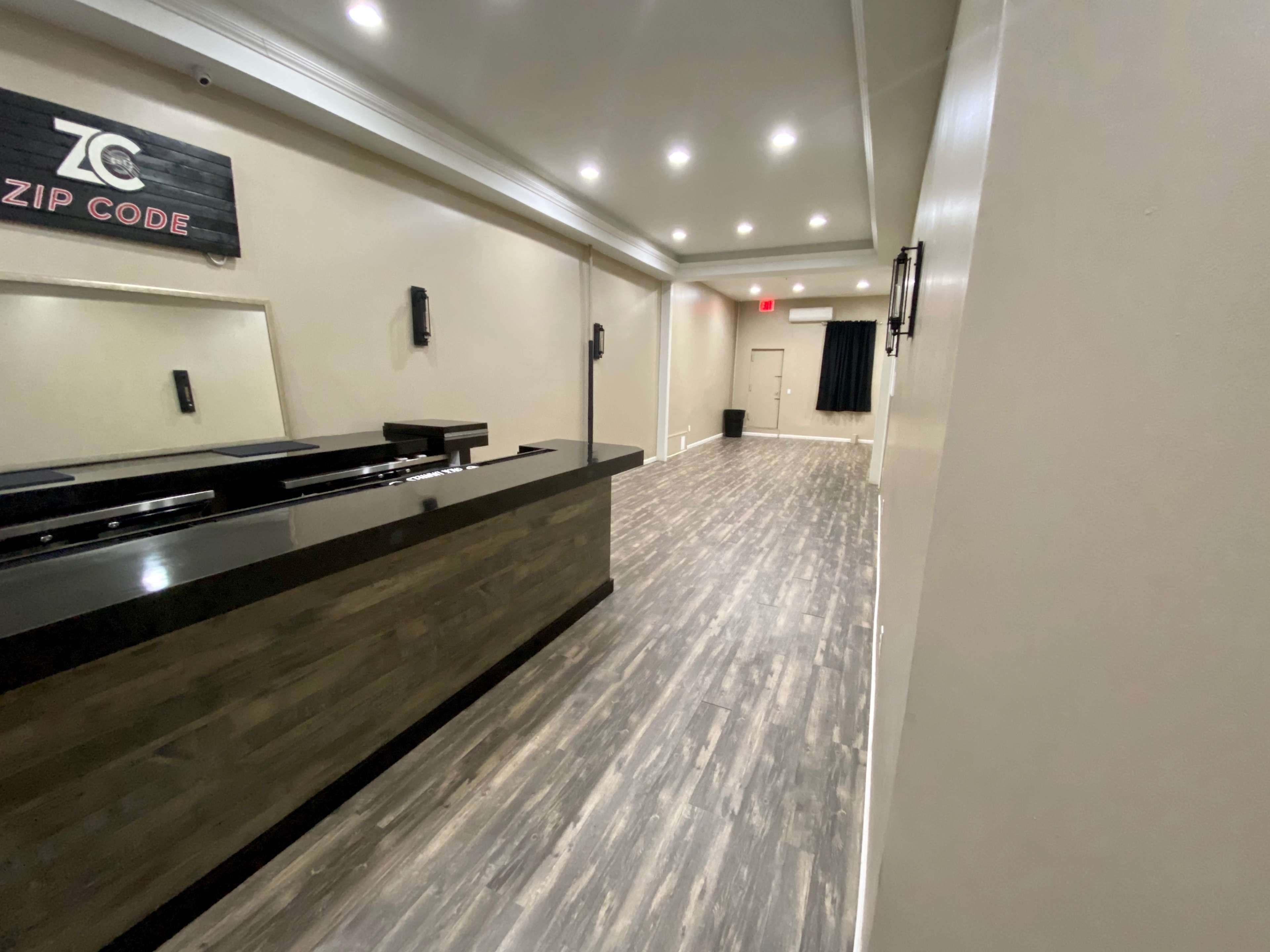 The image shows a long, narrow hallway with a dark counter on the left, illuminated by recessed lighting along the ceiling.