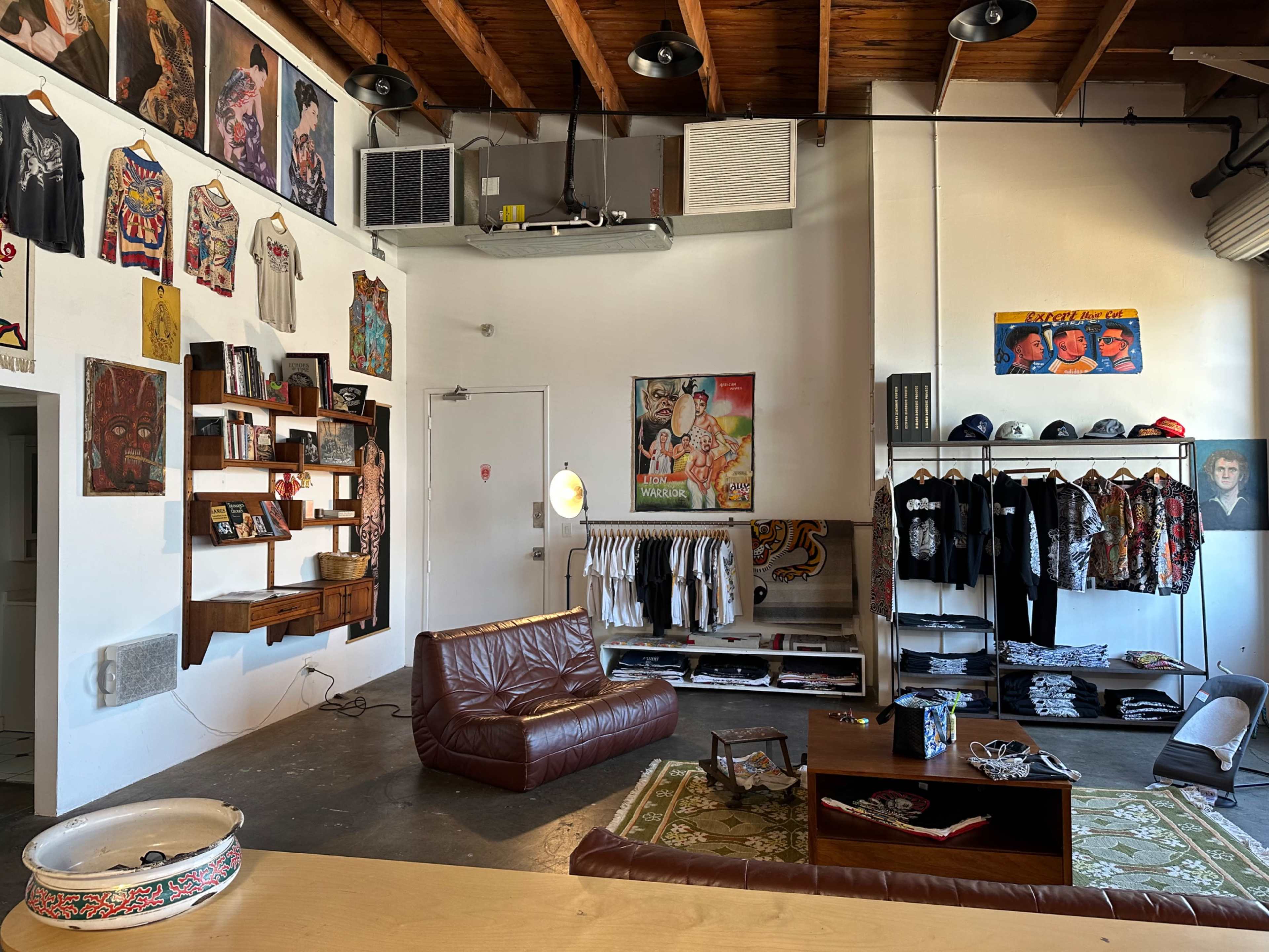 The image shows a stylish clothing store interior featuring a leather sofa, rack displays of apparel, and wall art.
