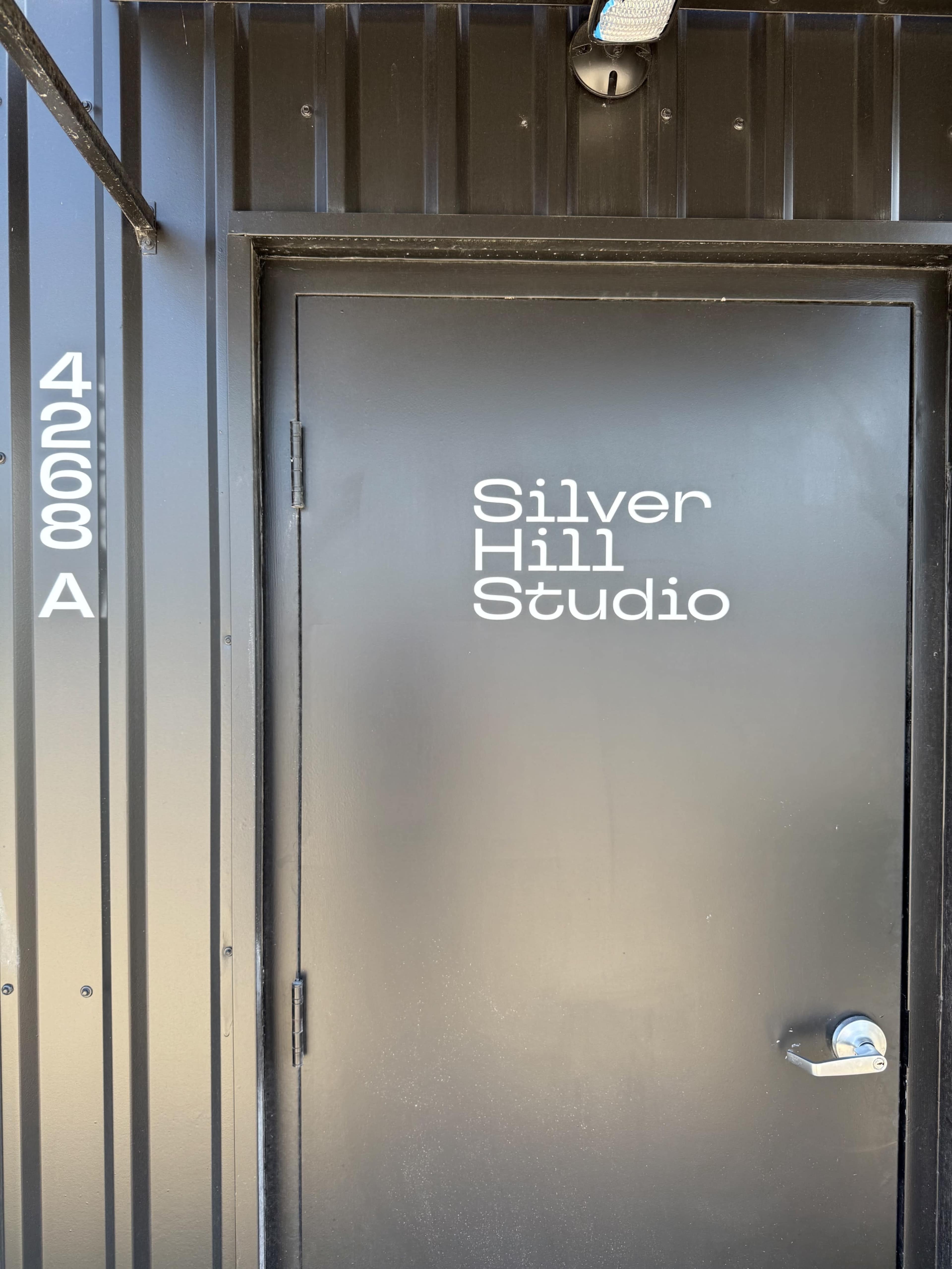 The image depicts a black door with the text "Silver Hill Studio" displayed in white lettering above the door handle.