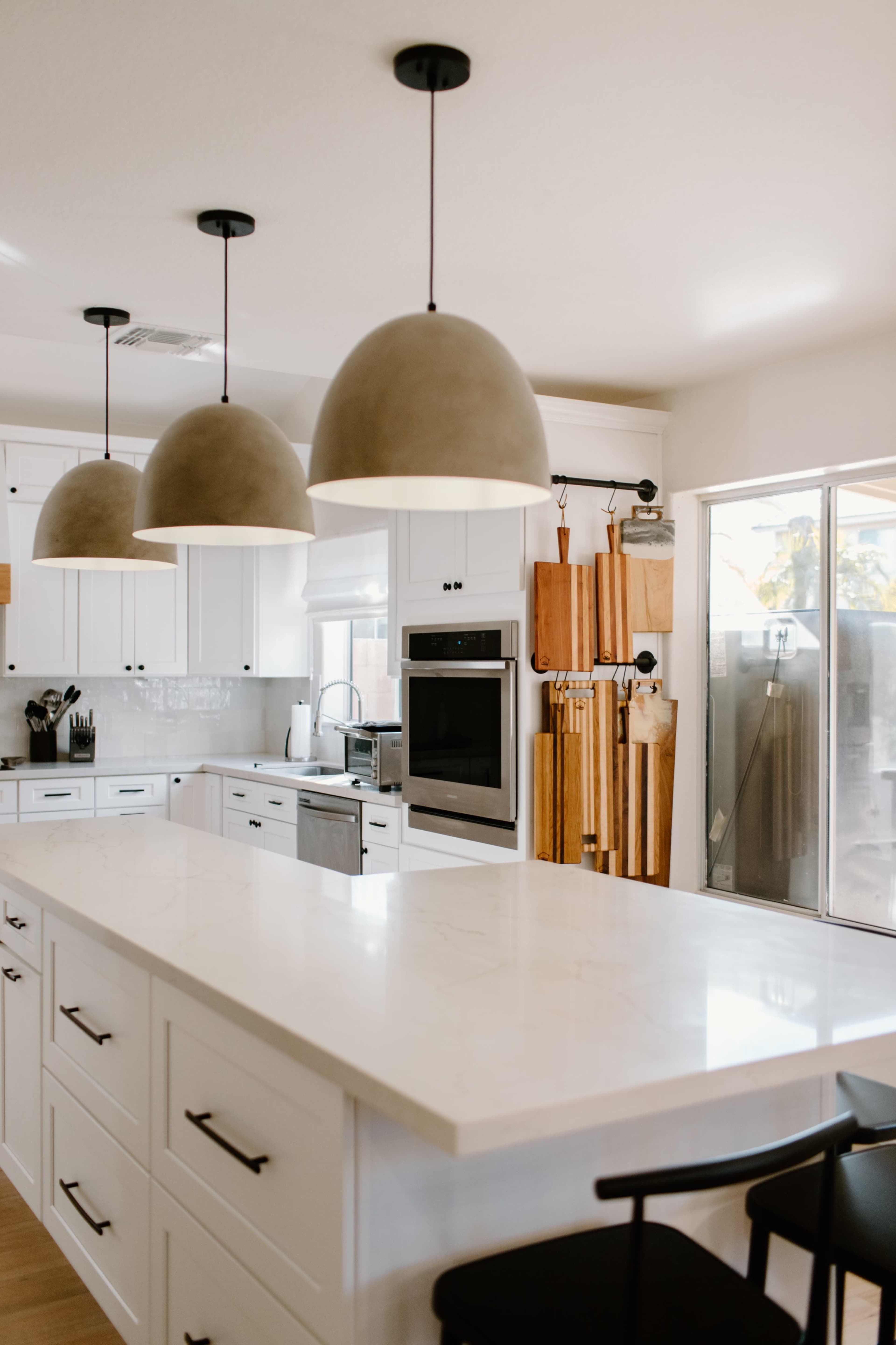 A modern kitchen features white cabinetry, a large island with a marble countertop, and three pendant lights hanging above.
