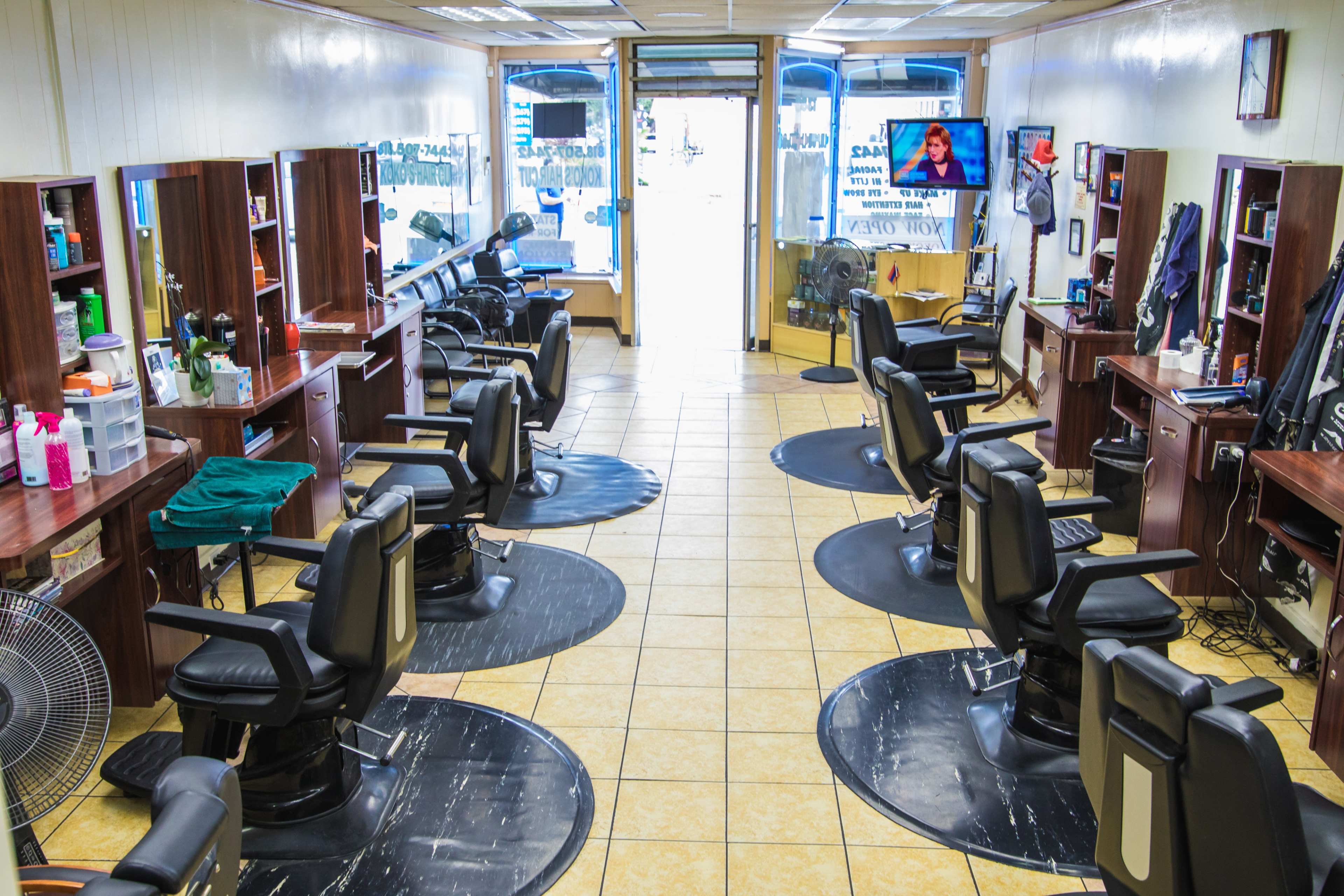The interior of a barber shop with multiple styling chairs, workstations, and a waiting area.