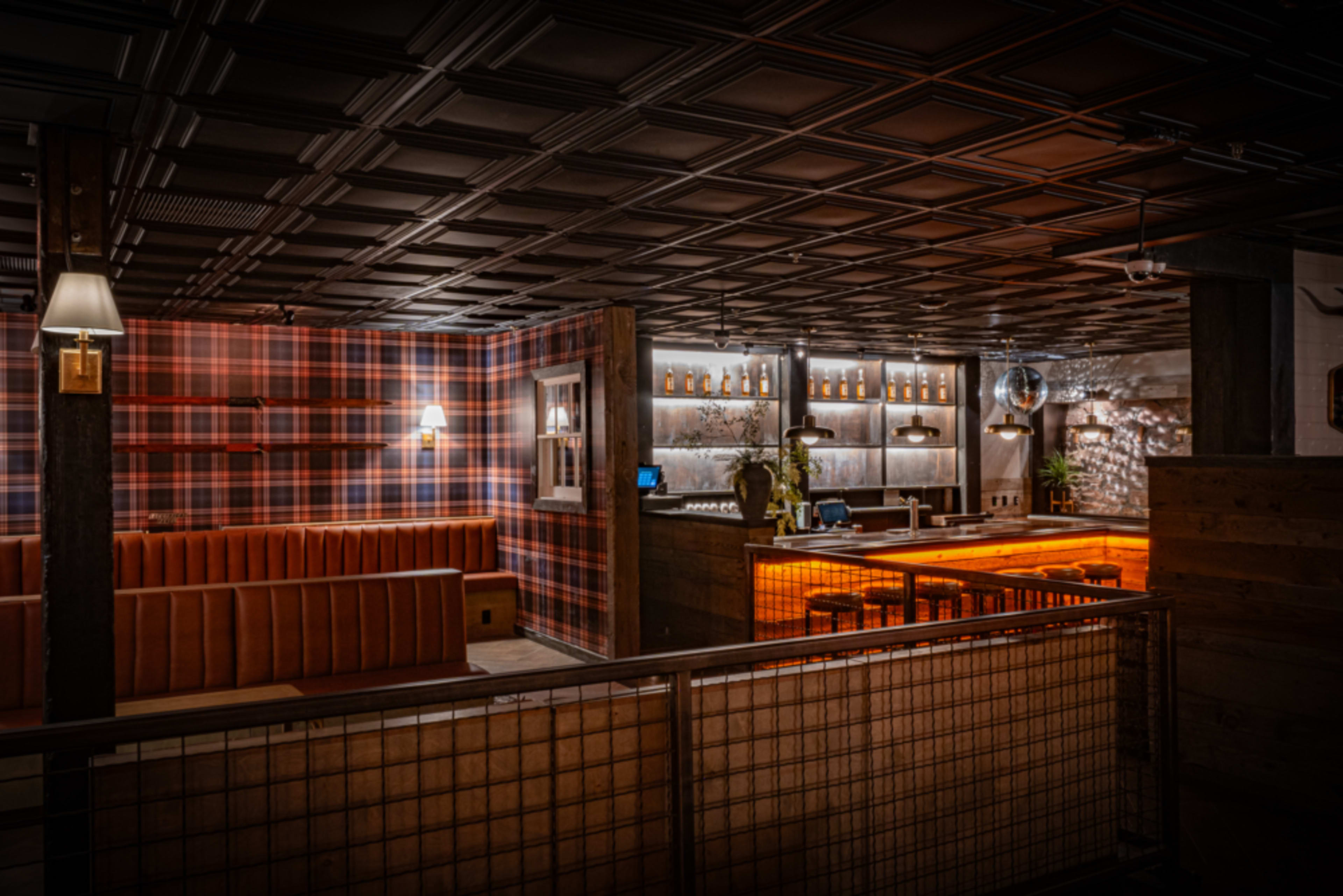 A restaurant interior with a plaid wall design, wooden accents, and a well-lit bar area.
